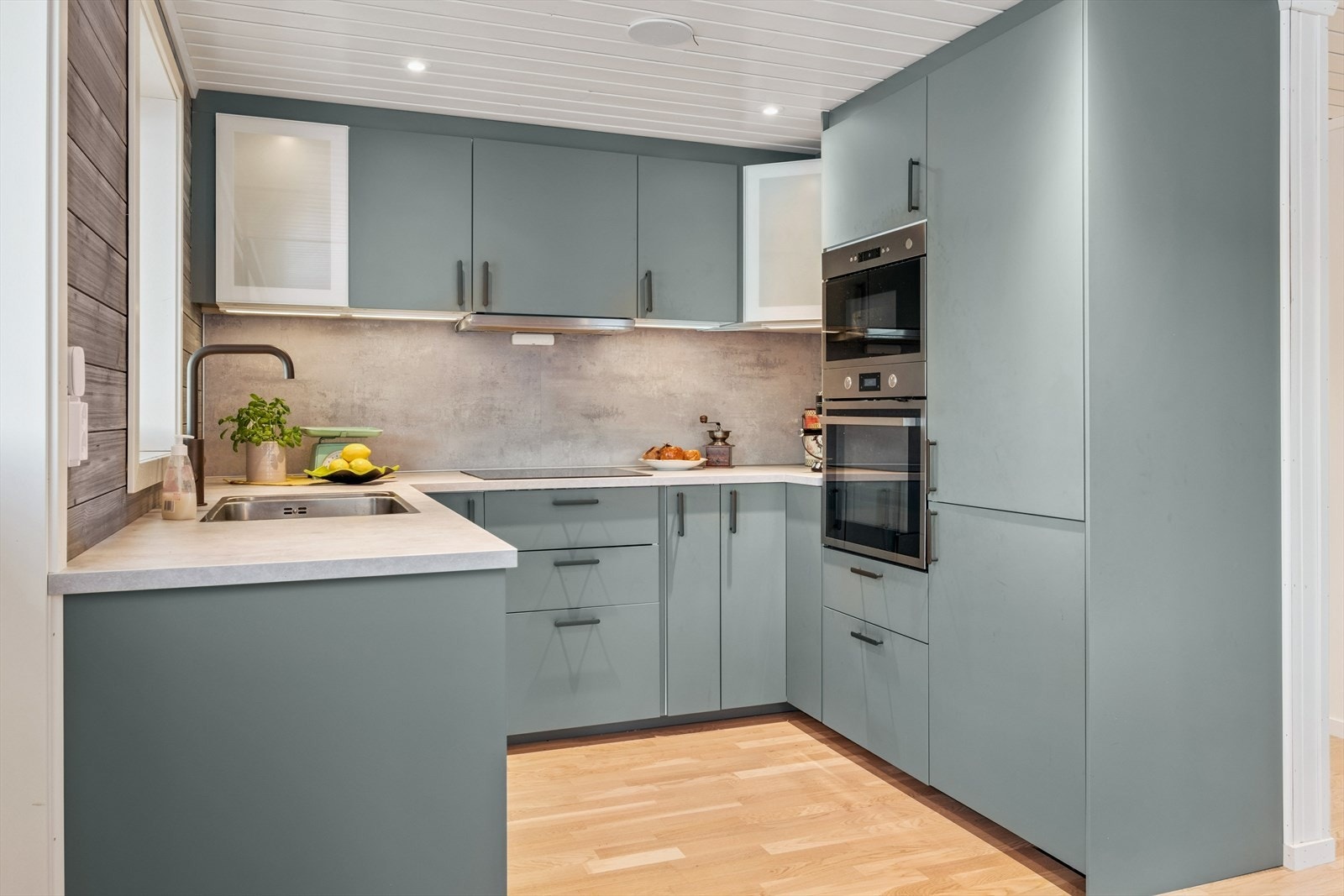 Stilrent kjøkken med integrerte hvitevarer som stekovn, mikrobølgeovn, kjøl- og fryseskap, oppvaskmaskin og platetopp Galleribilde