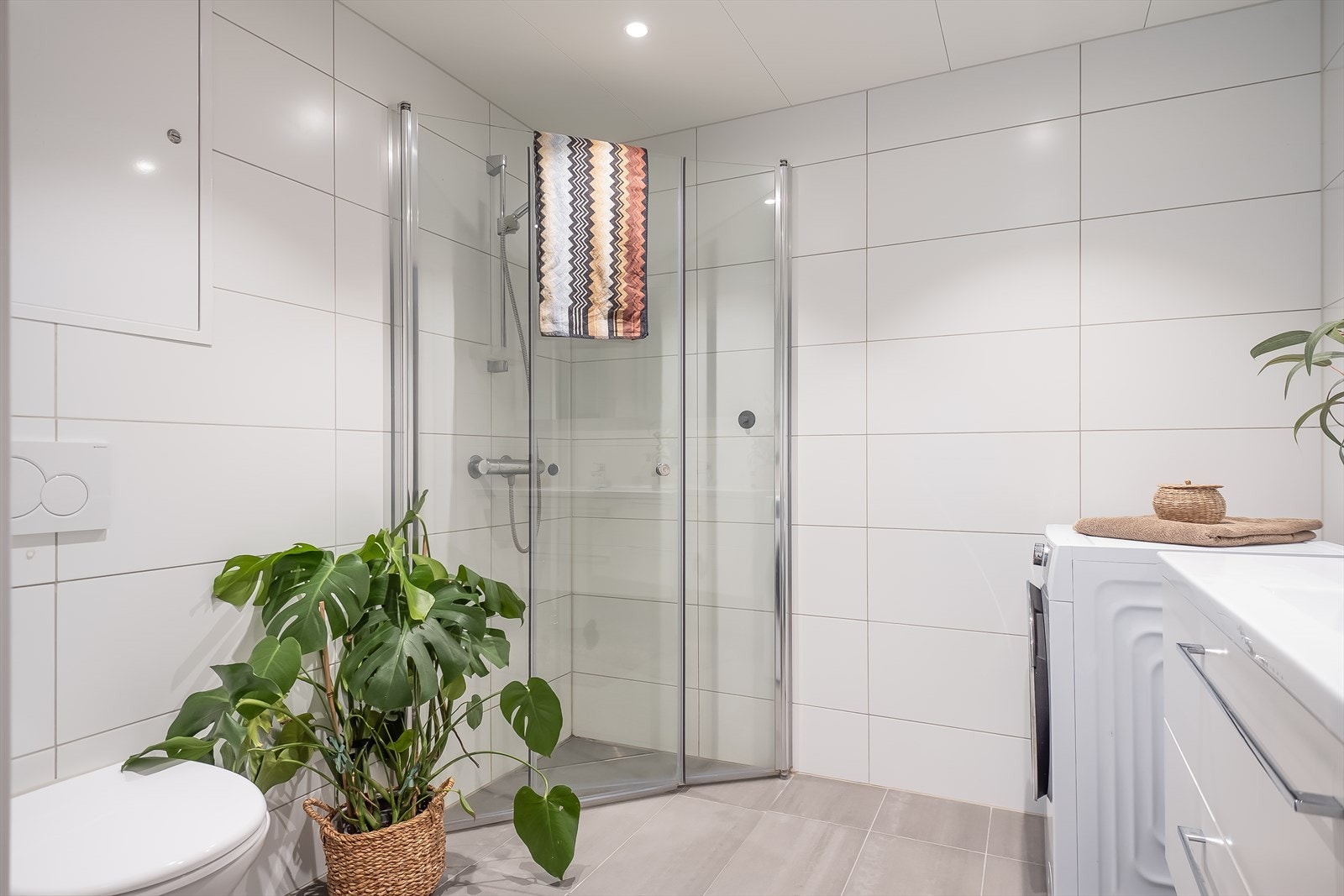 Baderommet er utstyrt med vegghengt toalett, behagelig gulvvarme, dusjhjørne med dusjgarnityr på vegg, samt opplegg for vaskemaskin. Galleribilde