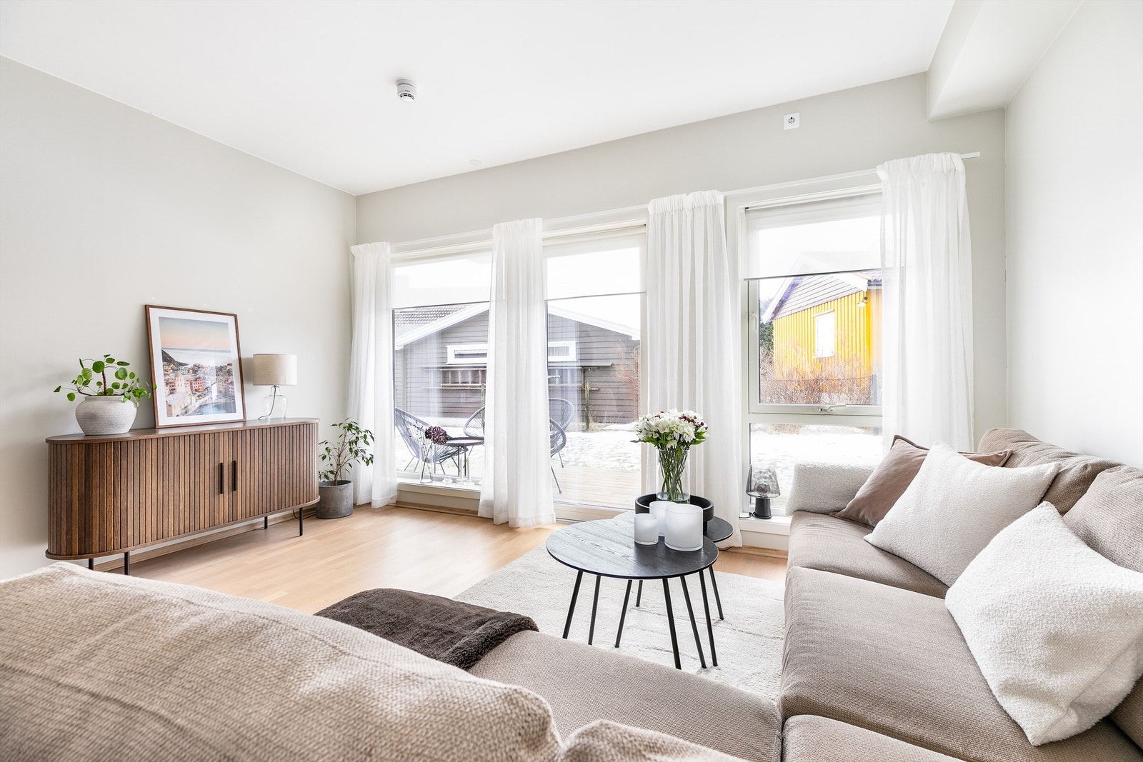 Store, vertikalstilte vinduer mot syd fyller stuen med naturlig lys. Galleribilde