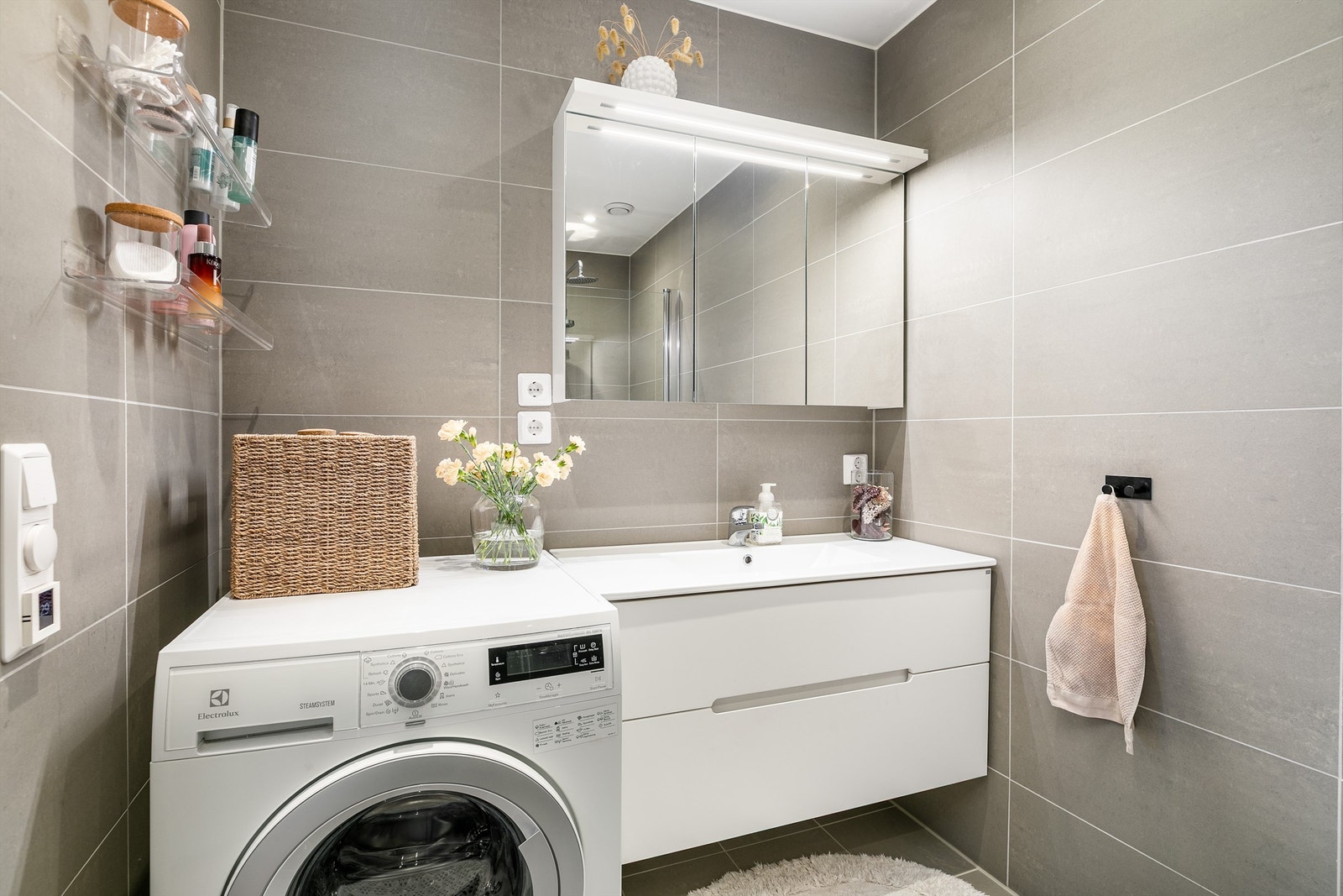 Grå fliser på både gulv og vegger skaper helhet på badet. I gulvet er det elektrisk varme. Galleribilde