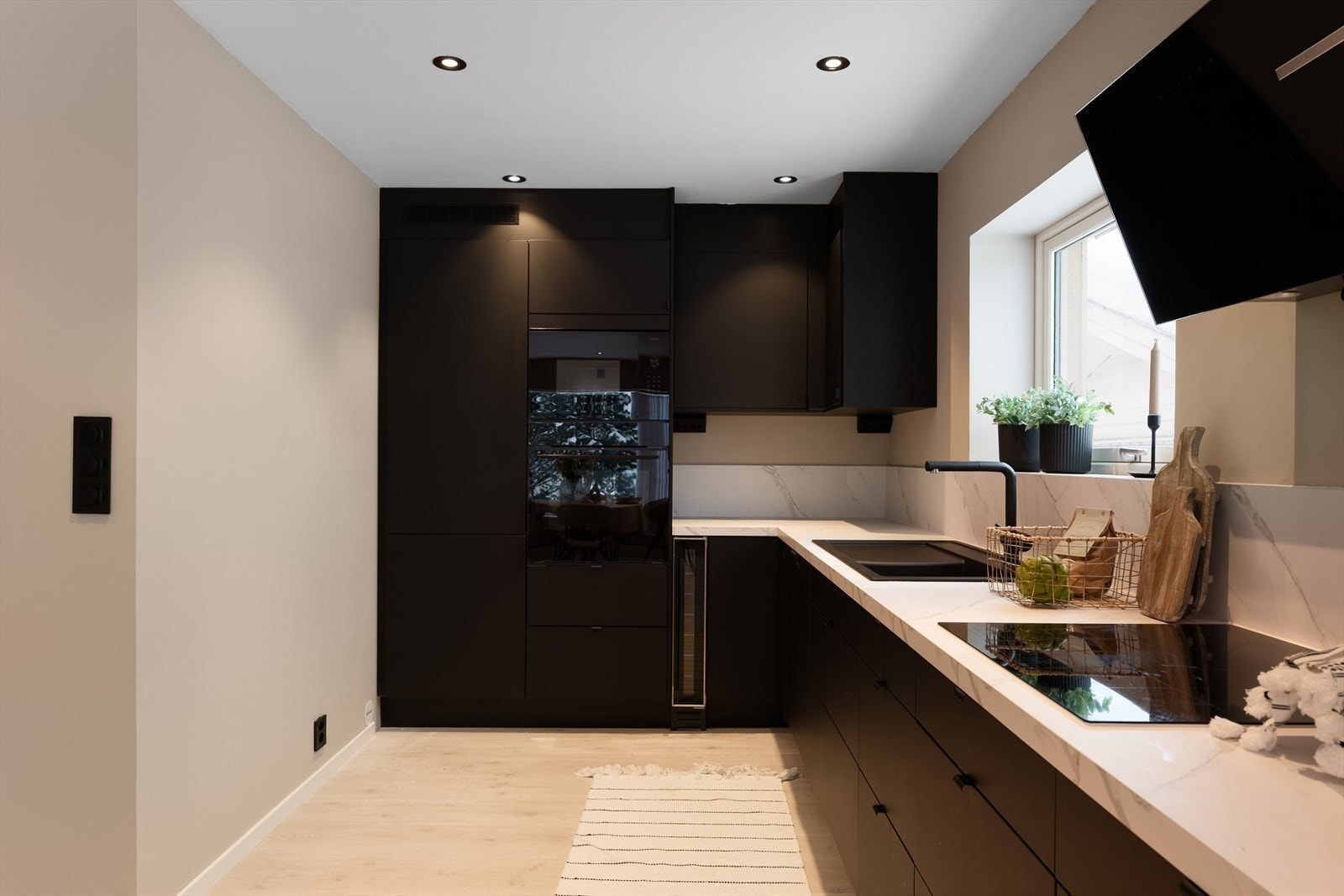 Sorte fronter, diskret håndtak og benkeplate i laminat med nedfelt kum. Galleribilde