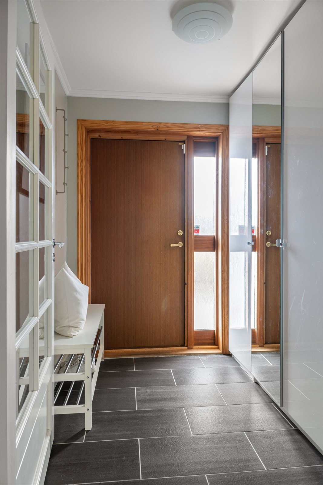 Entréen ønsker deg velkommen til en lys og romslig gang med fliser på gulv og stort garderobeskap. Galleribilde