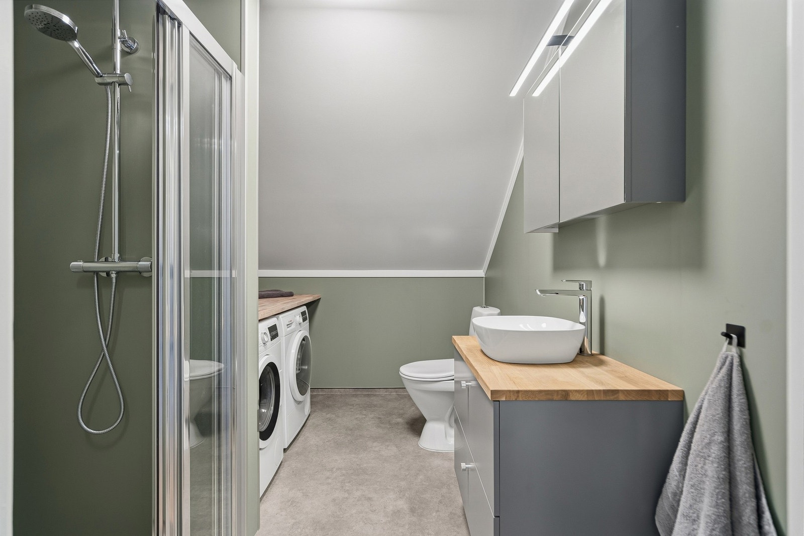 Badet er innredet med dusj, vask, toalett og opplegg til vaskemaskin Galleribilde