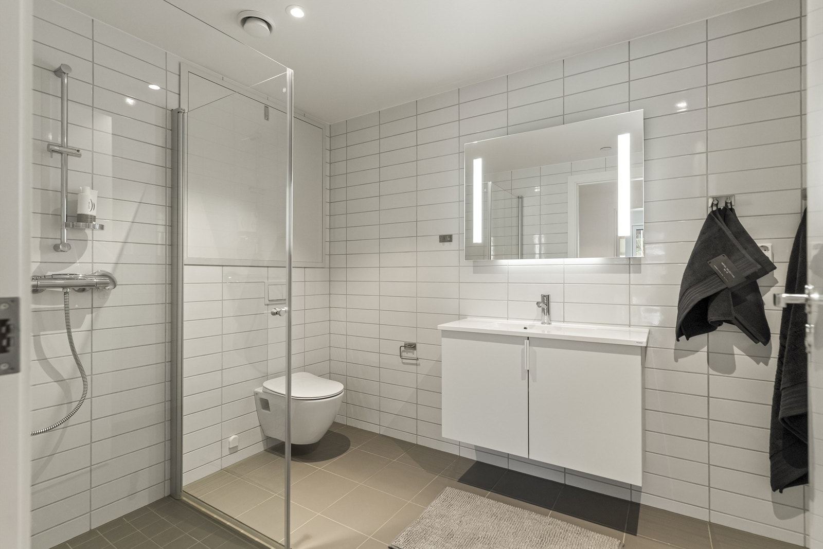 Det delikate badeværelset har flis på gulv og vegger og har god belysning med down lights Galleribilde