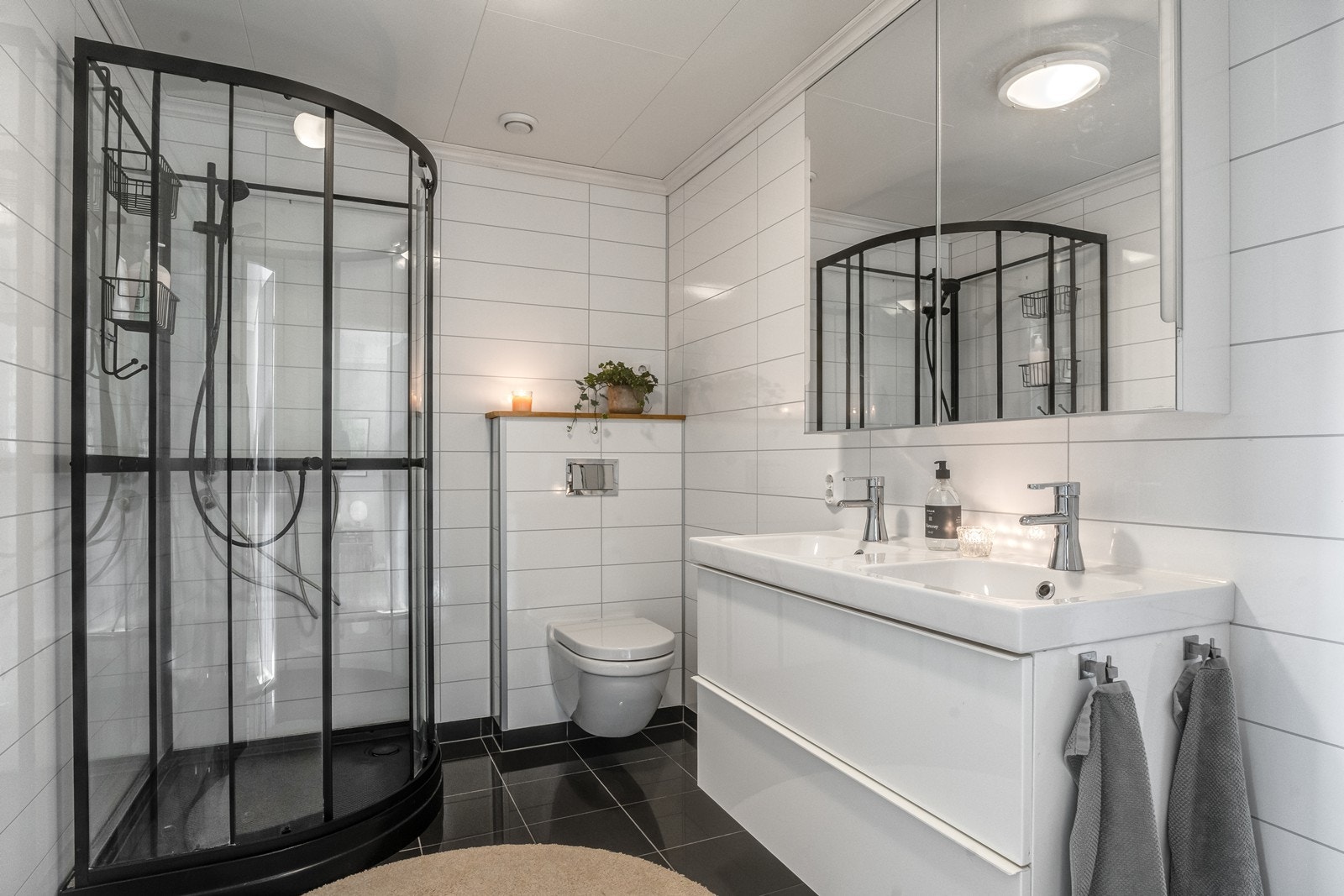 Lyst og tiltalende bad med flislagt gulv med behagelige varmekabler og lyse veggplater som gir rommet et moderne uttrykk. Galleribilde