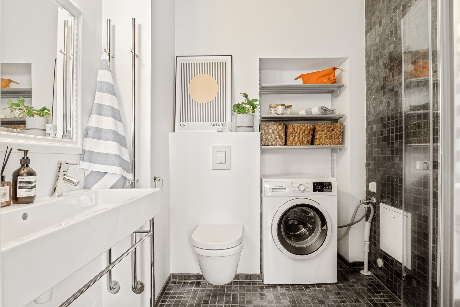 Badet er innredet med servant, veggmontert toalett og dusjløsning, samt opplegg for vaskemaskin. Rommet er oversiktlig utformet og dekker daglige behov på en god måte. Galleribilde