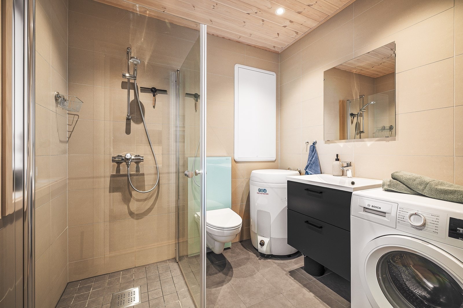 Badet er på ca. 4,3 kvm og har flislagte gulv og vegger samt trepanel i tak Galleribilde