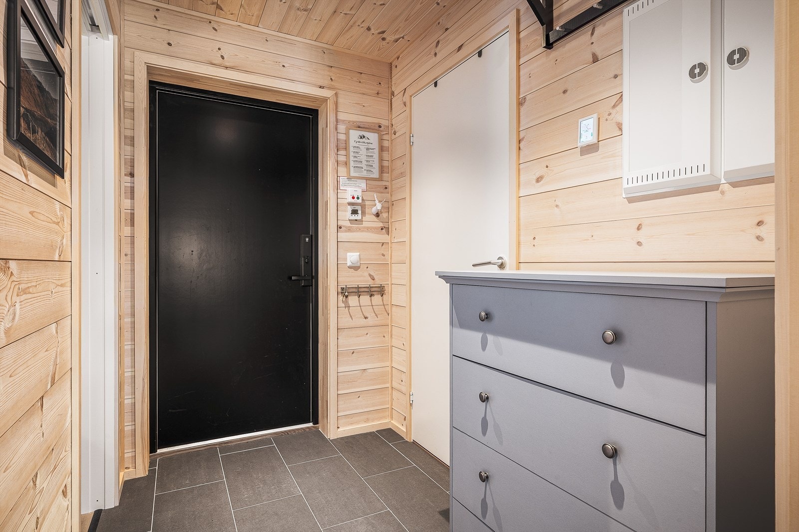 Entré/gang på ca. 3,4 kvm med flislagt gulv og gjennomgående trepanel på vegger og i tak Galleribilde
