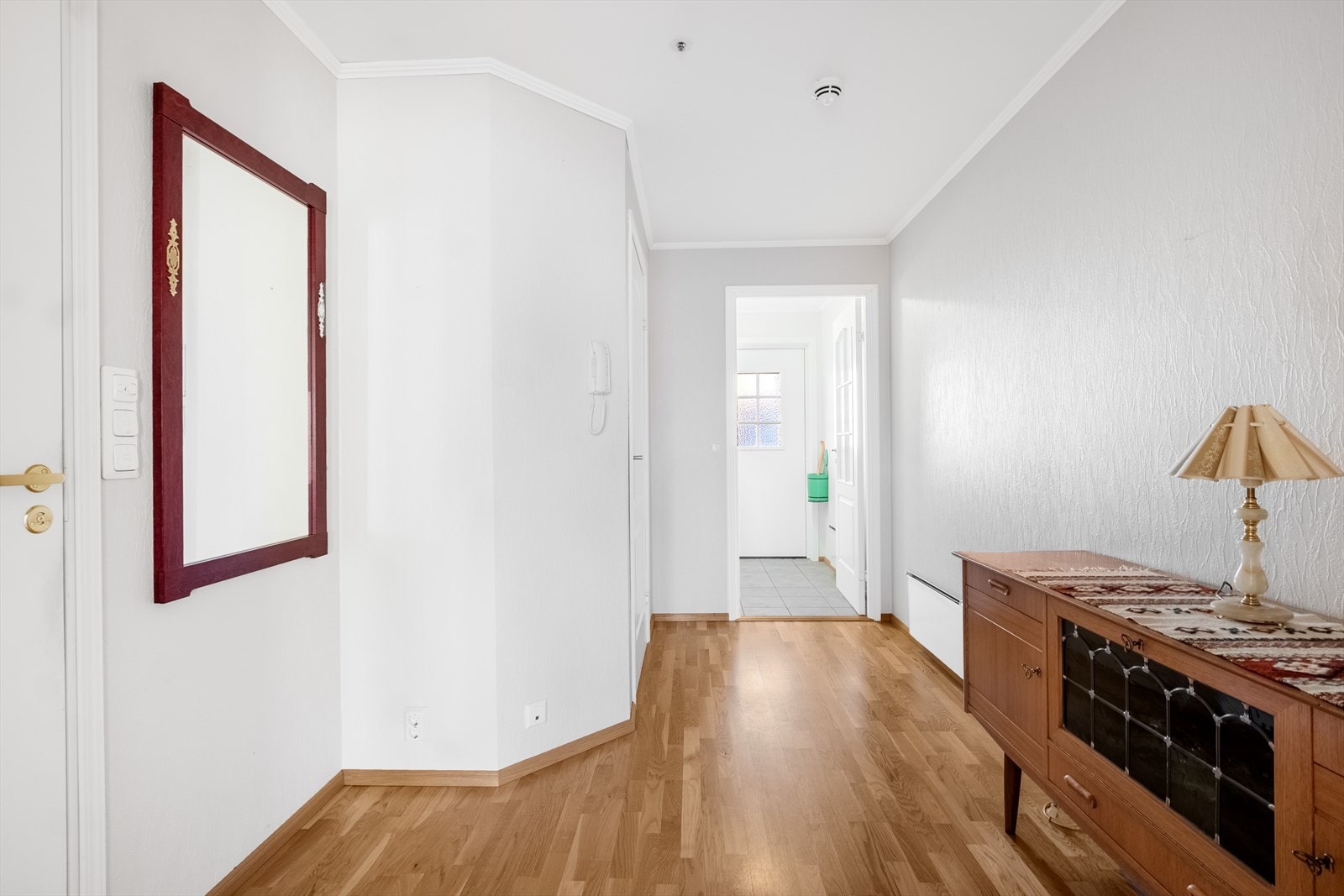 Entréen leder videre inn til en romslig gang med god plass til yttertøy og sko. Ryddige flater gir en funksjonell velkomstsone, og dørtelefon på veggen sørger for enkel og trygg adgangskontroll. Galleribilde