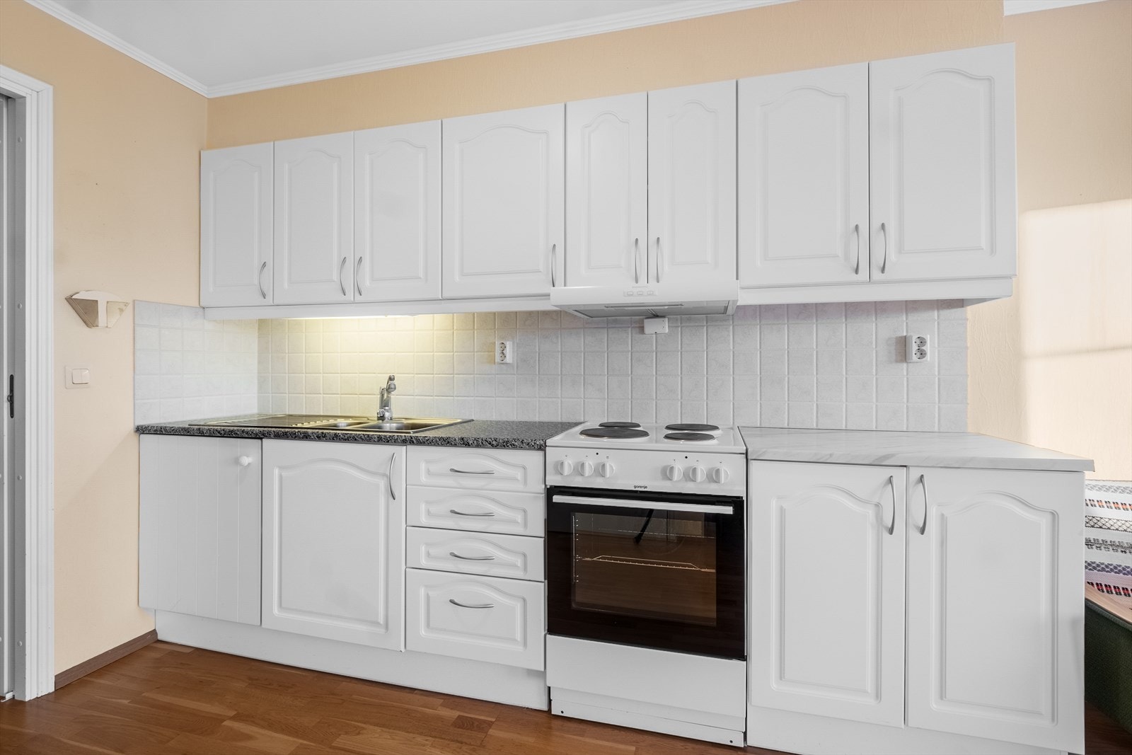 Den doble stålvasken med benkebeslag gir gode arbeidsflater, mens fliser over benken tilfører både beskyttelse og et rent uttrykk. Galleribilde