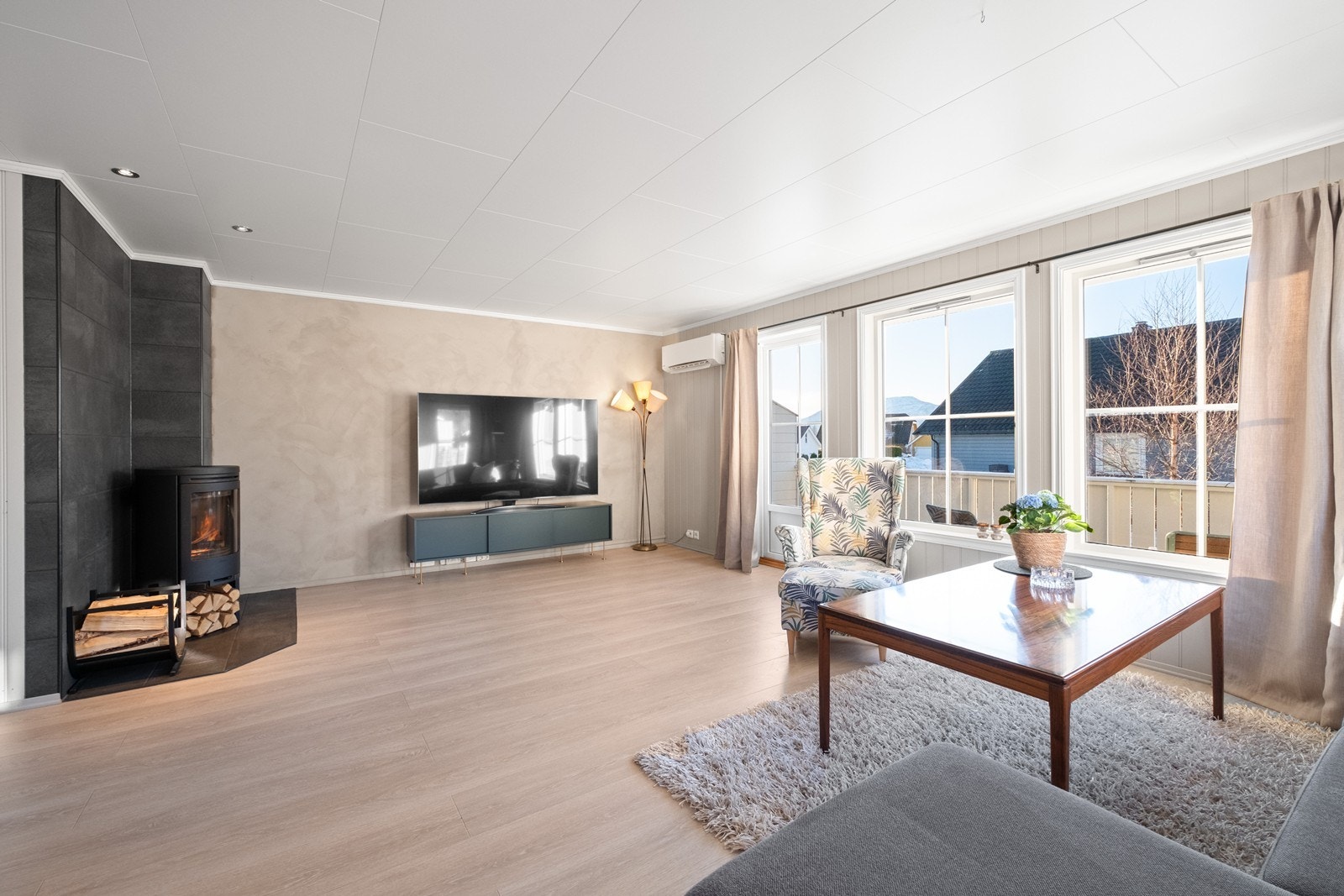 Store vindusflater sørger for godt med dagslys i rommet, og vedovn og varmepumpe gir effektiv oppvarming. Galleribilde