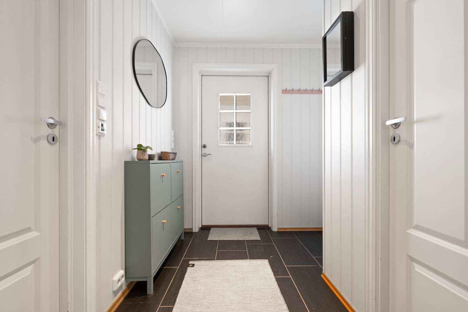 Entréen har flislagt gulv og panelplater på veggene, med plass til oppbevaring. Galleribilde