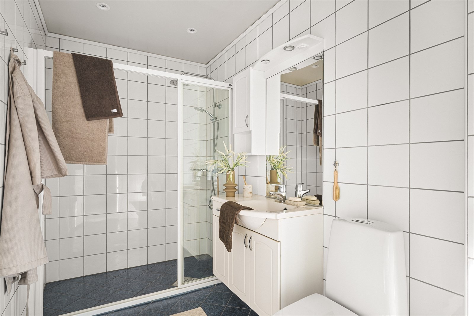 Badet er romslig og helfliset, innredet med nedfelt servant, toalett og dusjvegg Galleribilde