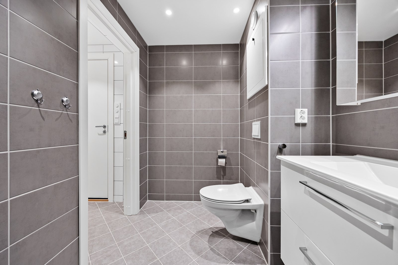 Rommet er elegant flislagt og utstyrt med vegghengt klosett og porselensservant. Galleribilde