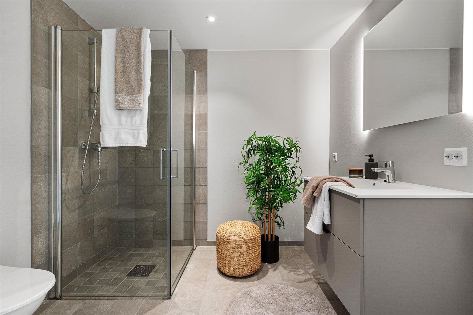 Delikat baderom med god gulvplass, varmekabler i gulv, servantseksjon med oppbevaring og gjennomtenkt belysning. Badet fremstår både funksjonelt og moderne. Galleribilde