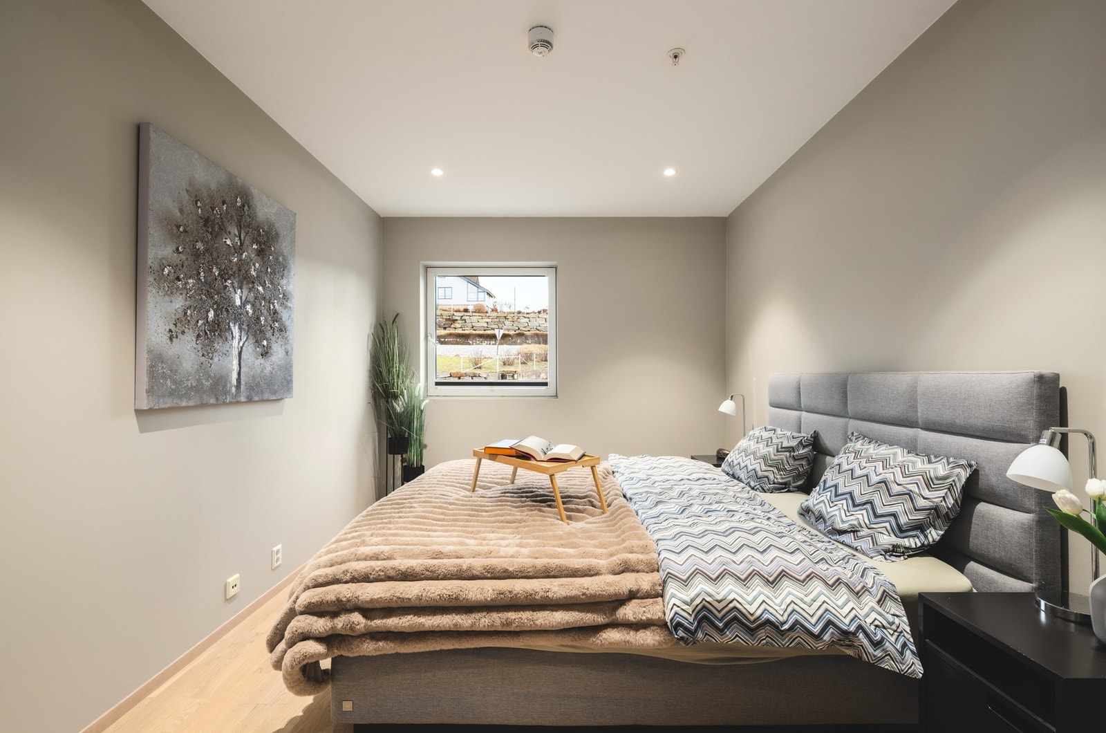 Soverom med vindu, lys grå vegger og parkettgulv. Galleribilde