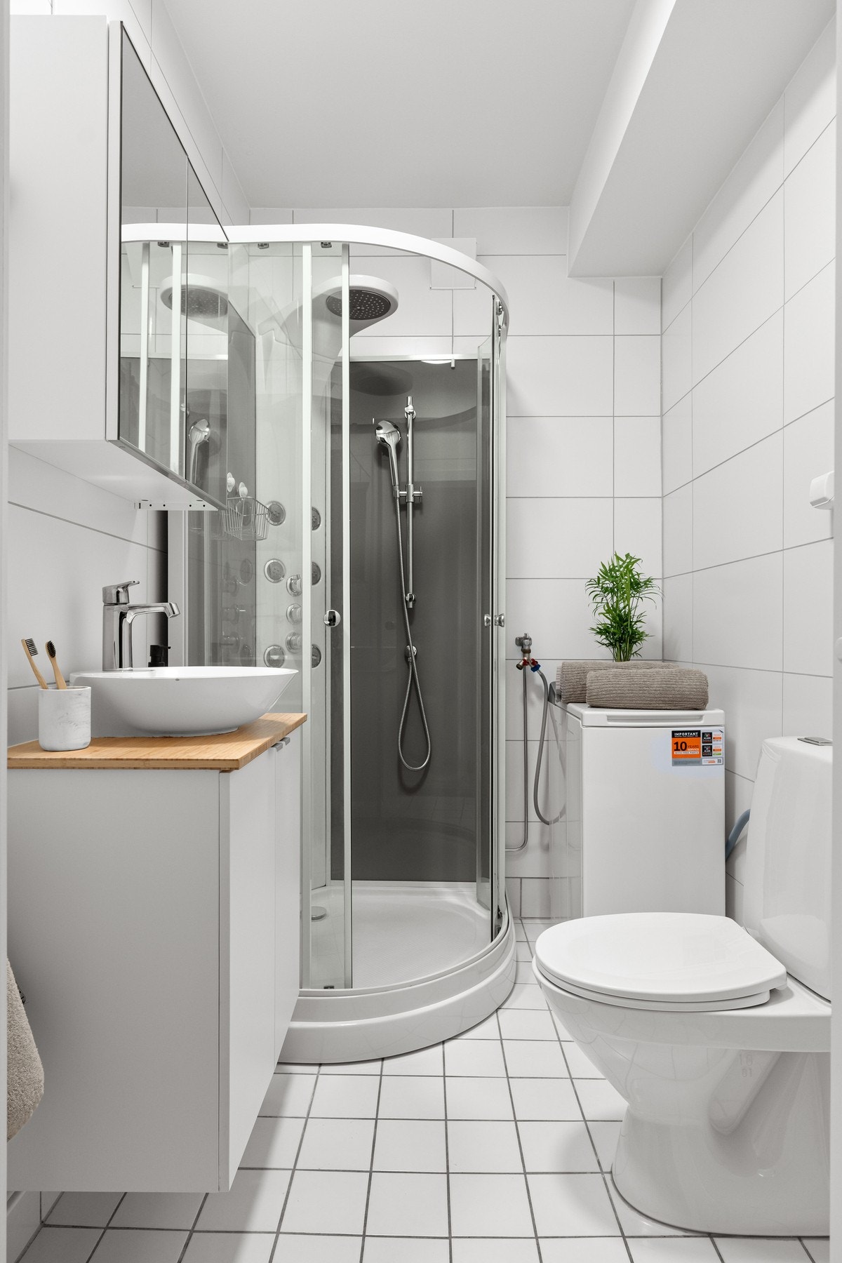 Praktisk bad med flislagt gulv, dusjkabinett og opplegg for vaskemaskin. Det er også felles vaskerom i borettslaget. Galleribilde