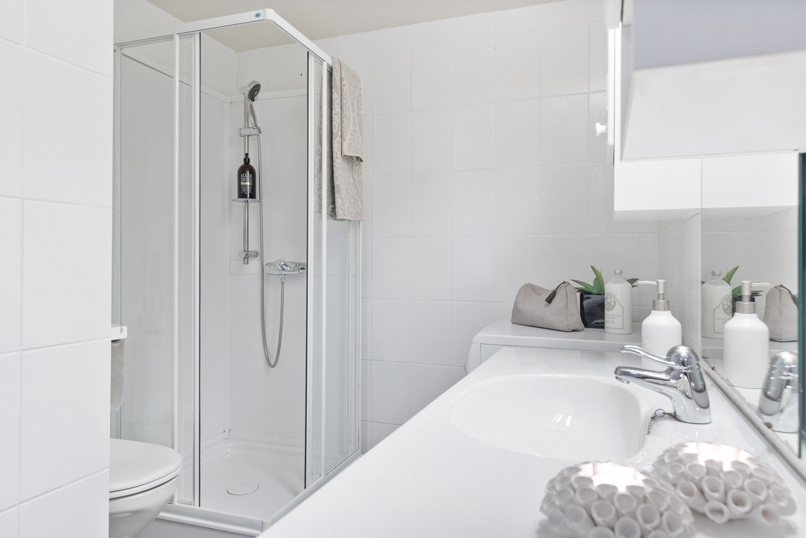 Flislagt bad på 3m². Badet er utstyrt med dusjkabinett, innredning med servant, toalett, og opplegg for vaskemaskin. Galleribilde