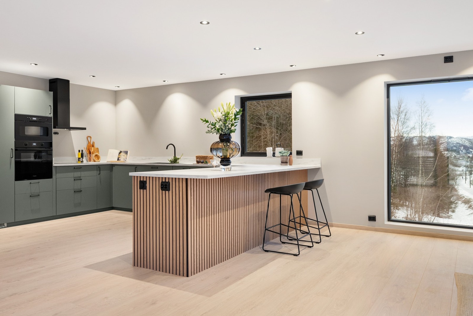 Stue og kjøkken i åpen løsning som danner et naturlig samlingspunkt i boligen Galleribilde