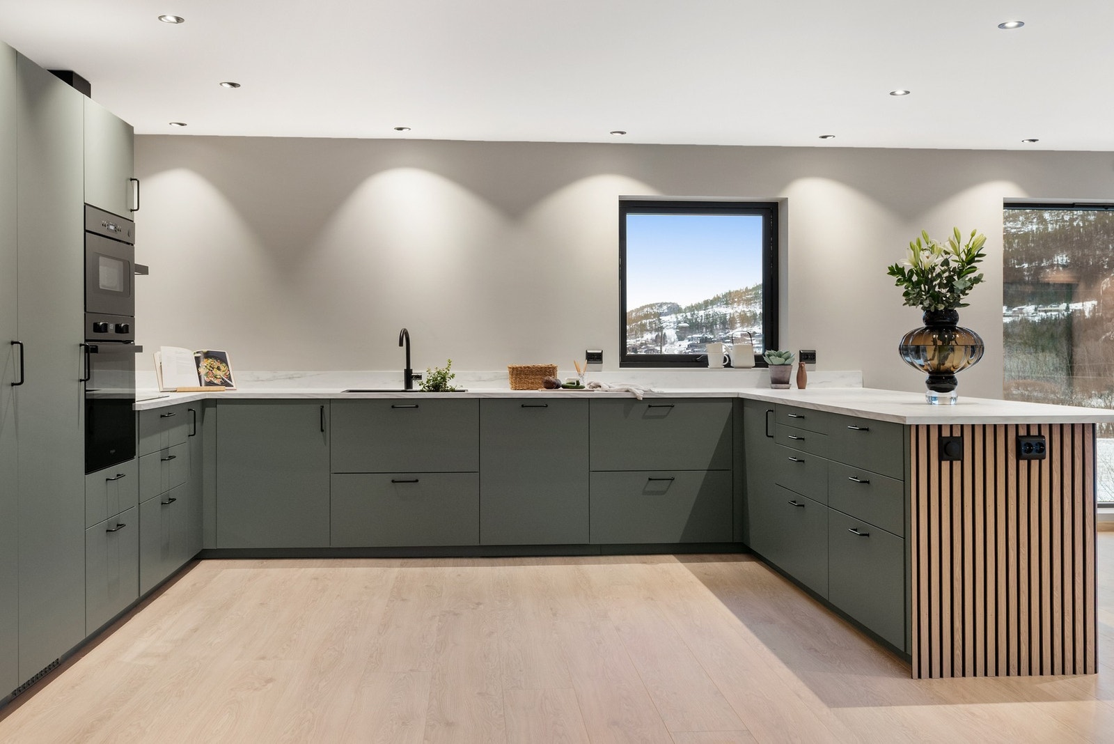 Kjøkken i tidsriktig grønt, kombinert med trespiler som skaper fin harmoni Galleribilde