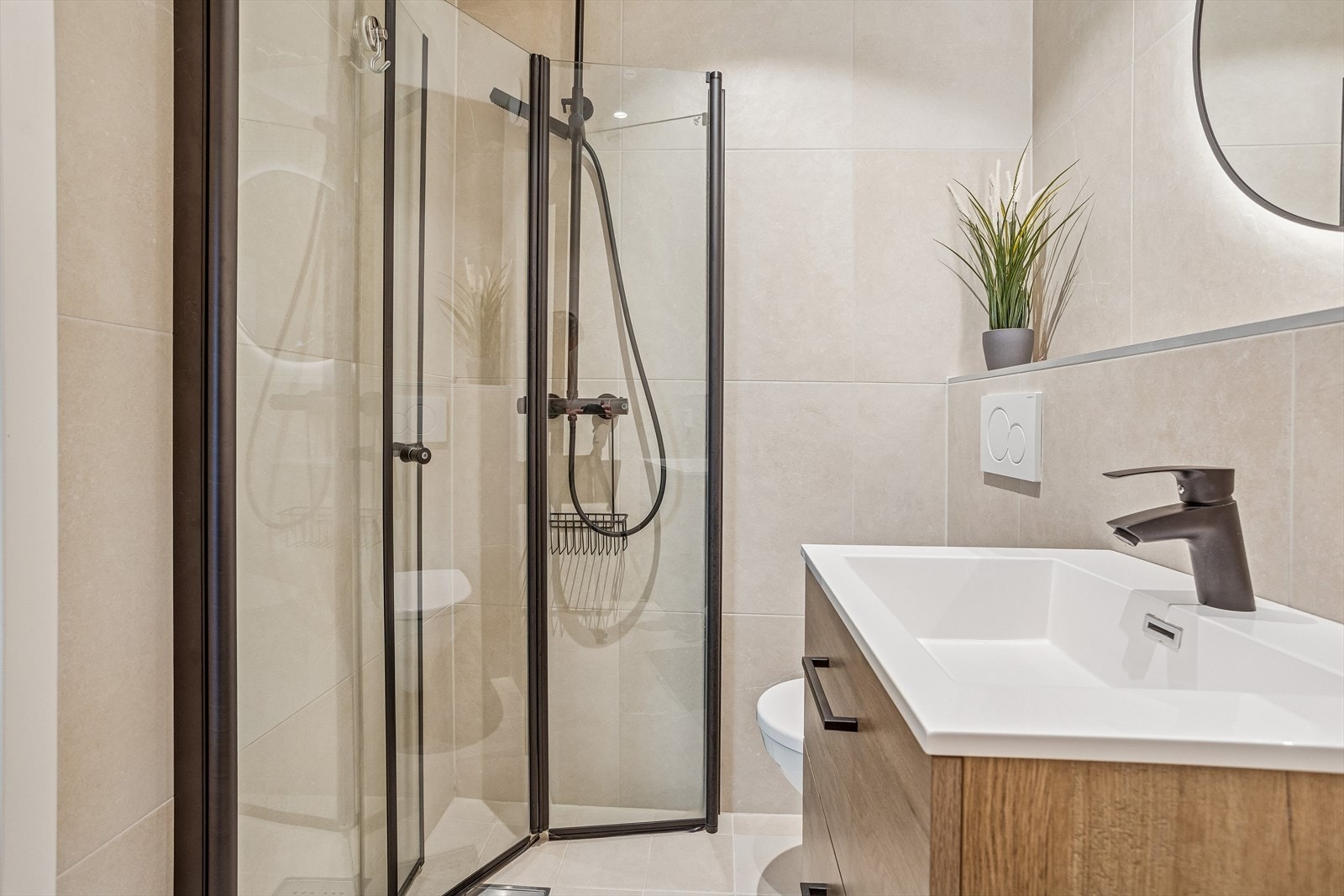 Rommet er utstyrt med vegghengt toalett, dusjdører i klart glass og opplegg for vaskemaskin. Galleribilde