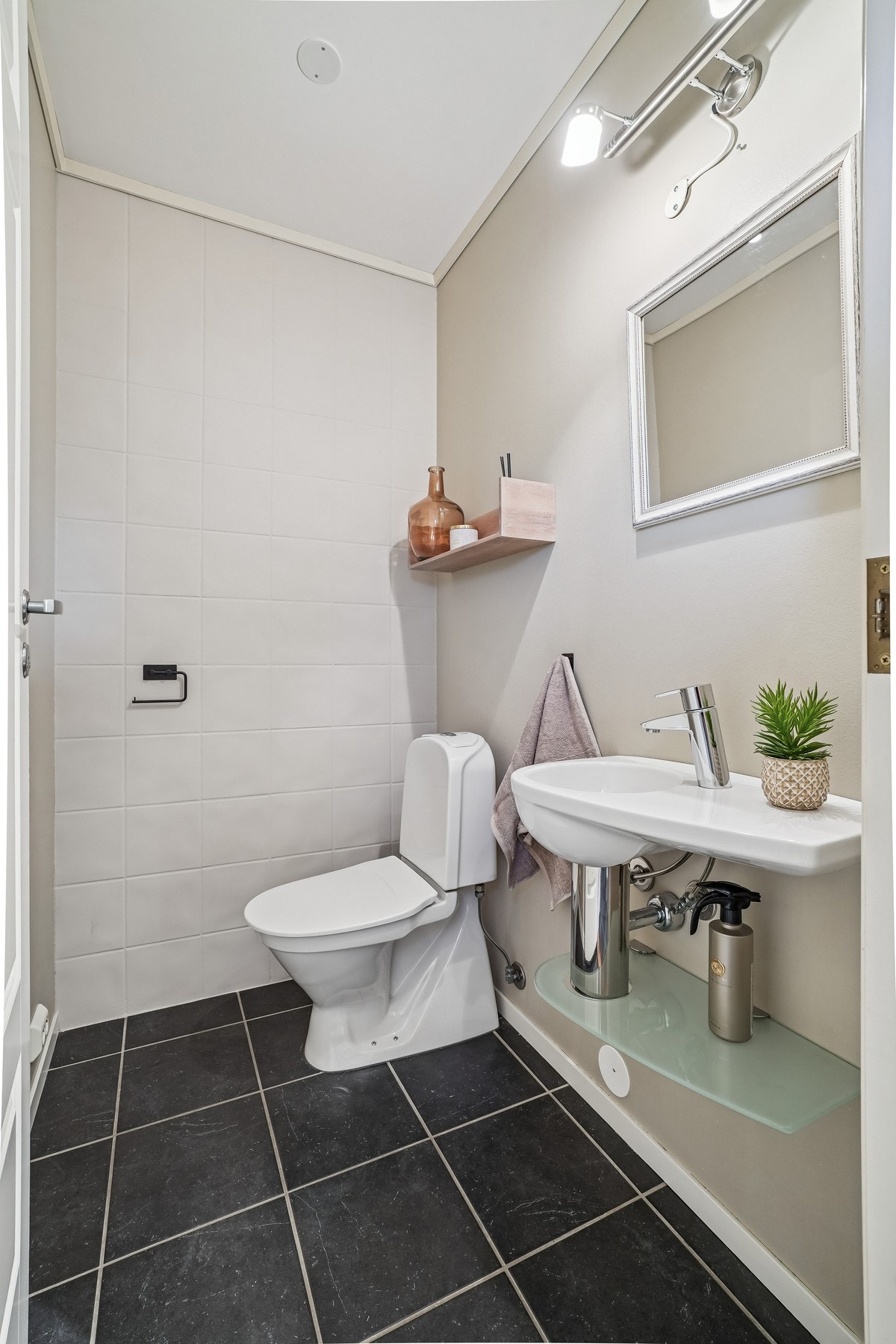 Separat toalettrom med fliser på gulvet. Utstyrt med toalett, servant og speil. Galleribilde