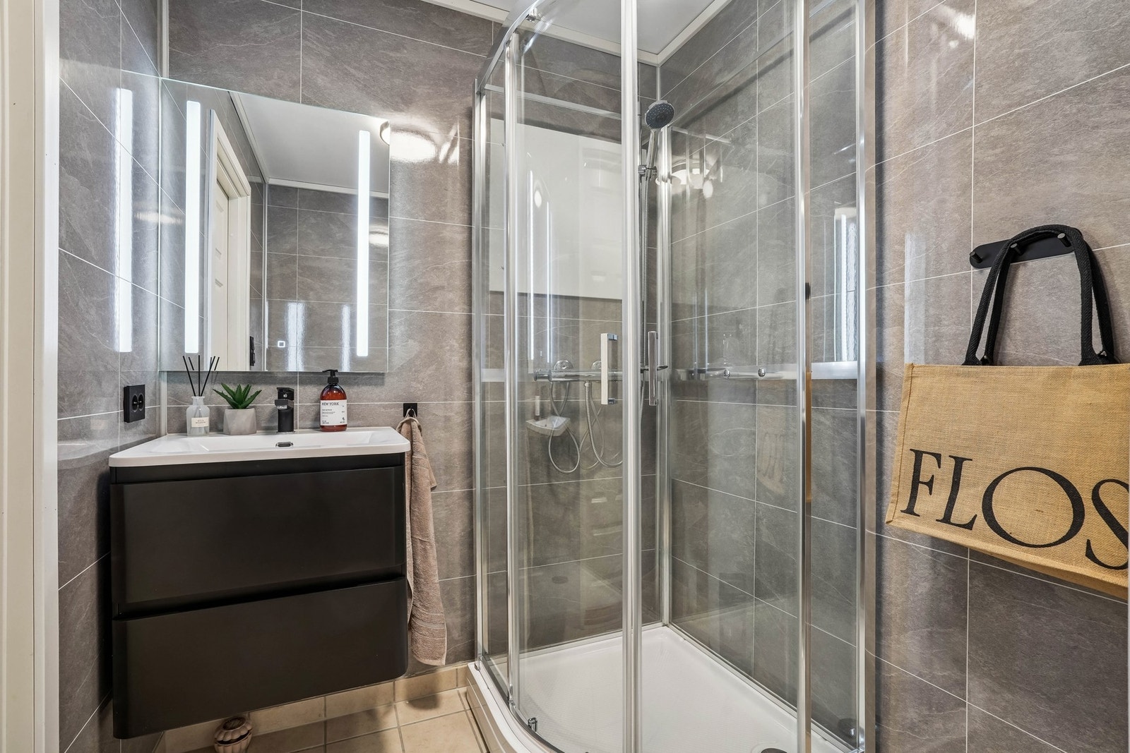 Pent bad med våtromsplater på vegger og flislagt gulv med elektriske varmekabler. Innredet med servantinnredning, speilskap med integrert belysning og dusjkabinett. Galleribilde