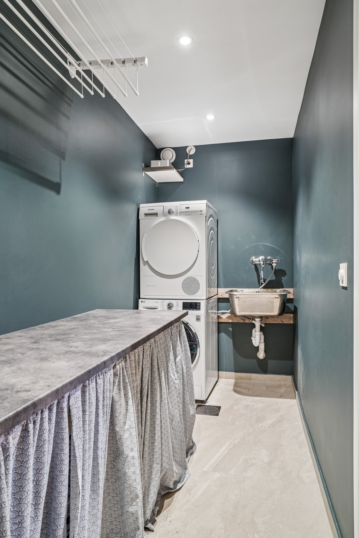 Praktisk vaskerom med flislagt gulv og malte flater. Innredet med opplegg for vaskemaskin, stålkum og laminat benkeplate. Galleribilde