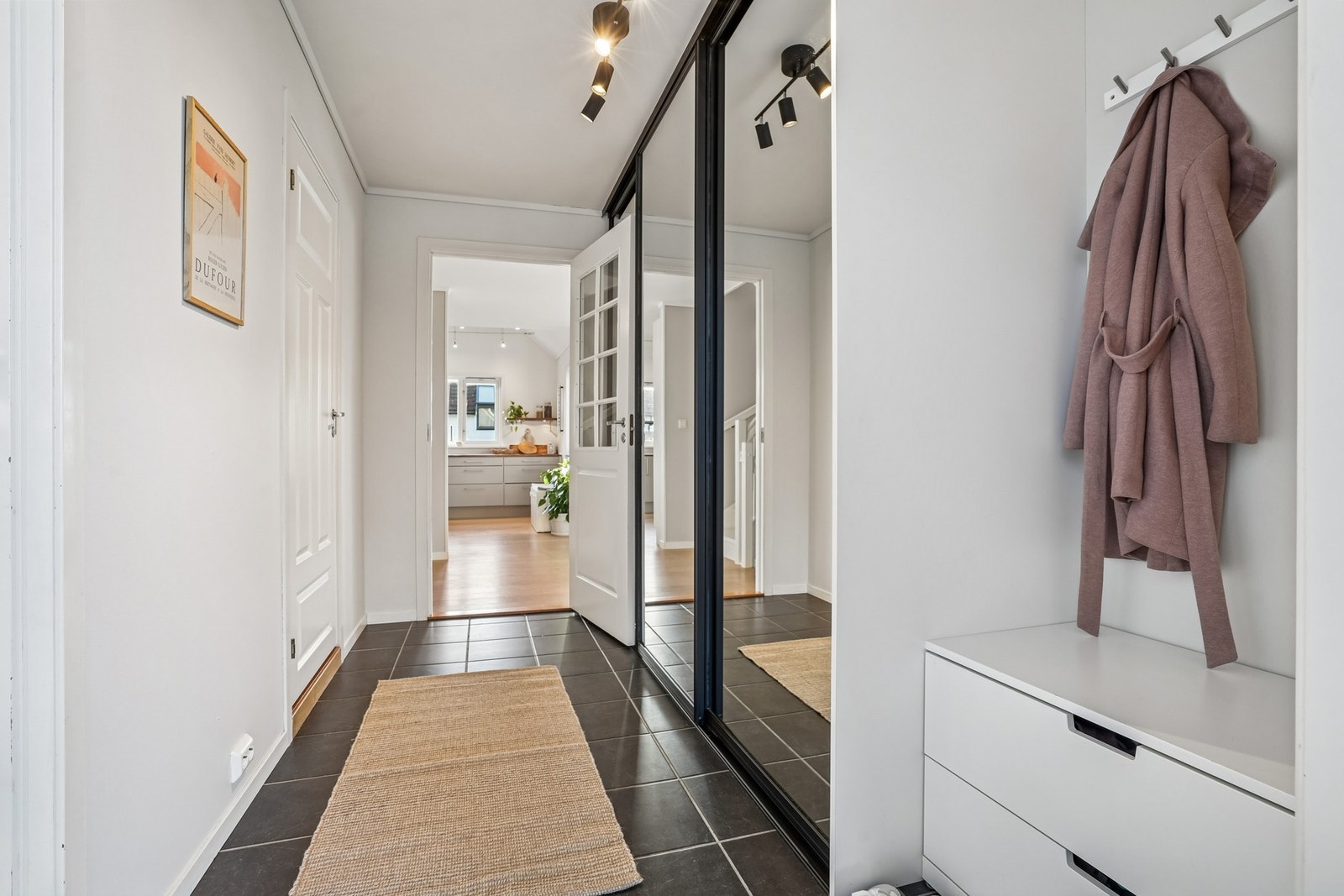 Lys entré med flislagt gulv og gulvvarme. Her kan man enkelt stue bort sko- og yttertøy i skyvedørsgarderoben. Galleribilde