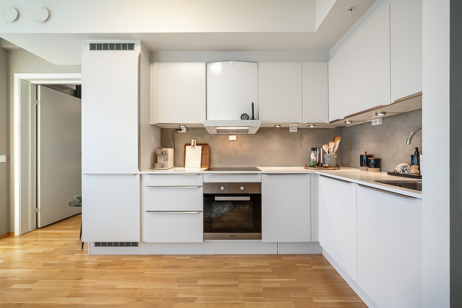 Kjøkkenet har en tidløs innredning med glatte fronter og integrerte hvitevarer Galleribilde