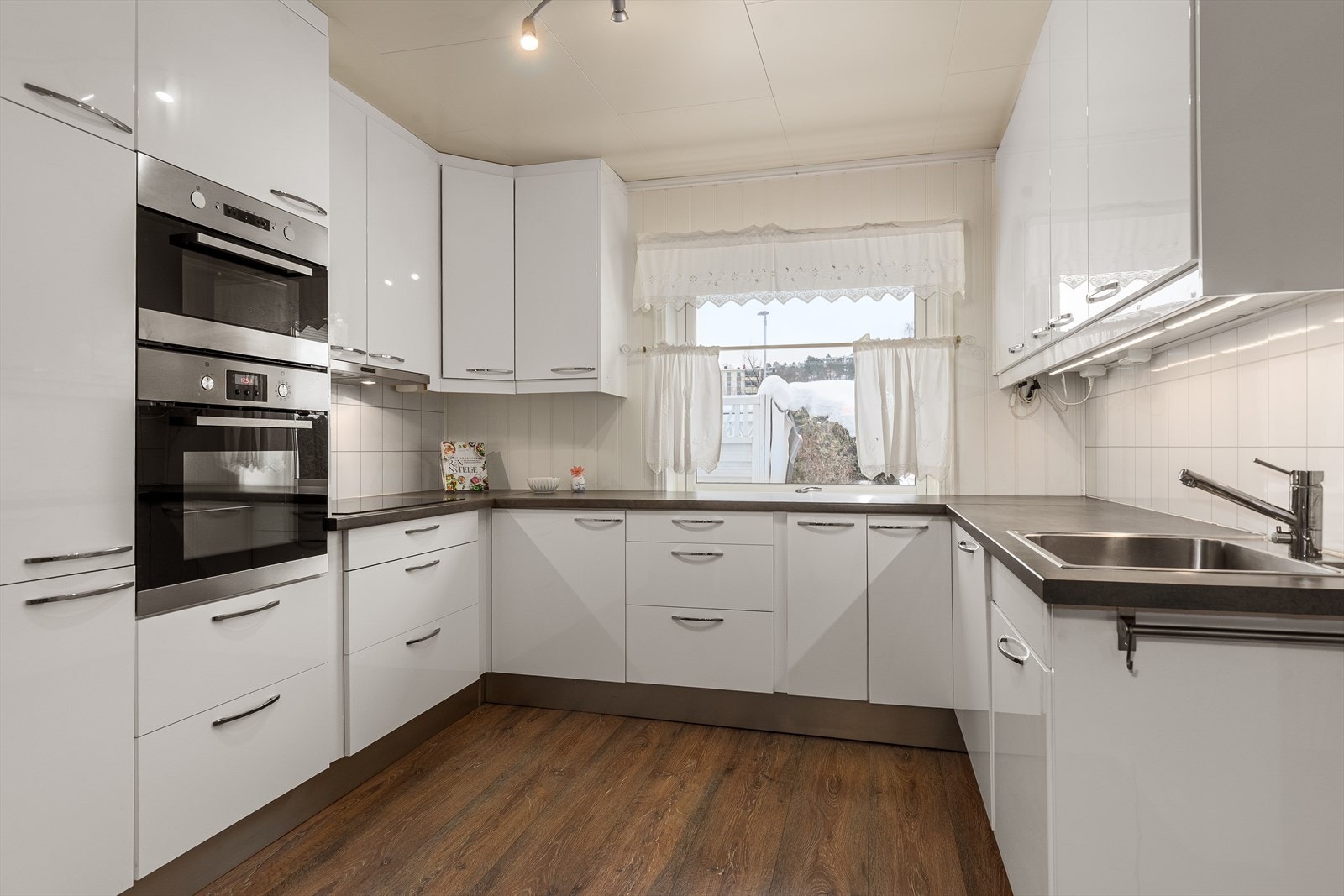 Kjøkkenet er utstyrt med hvitevarer som induksjonstopp, stekeovn, mikrobølgeovn og oppvaskmaskin Galleribilde