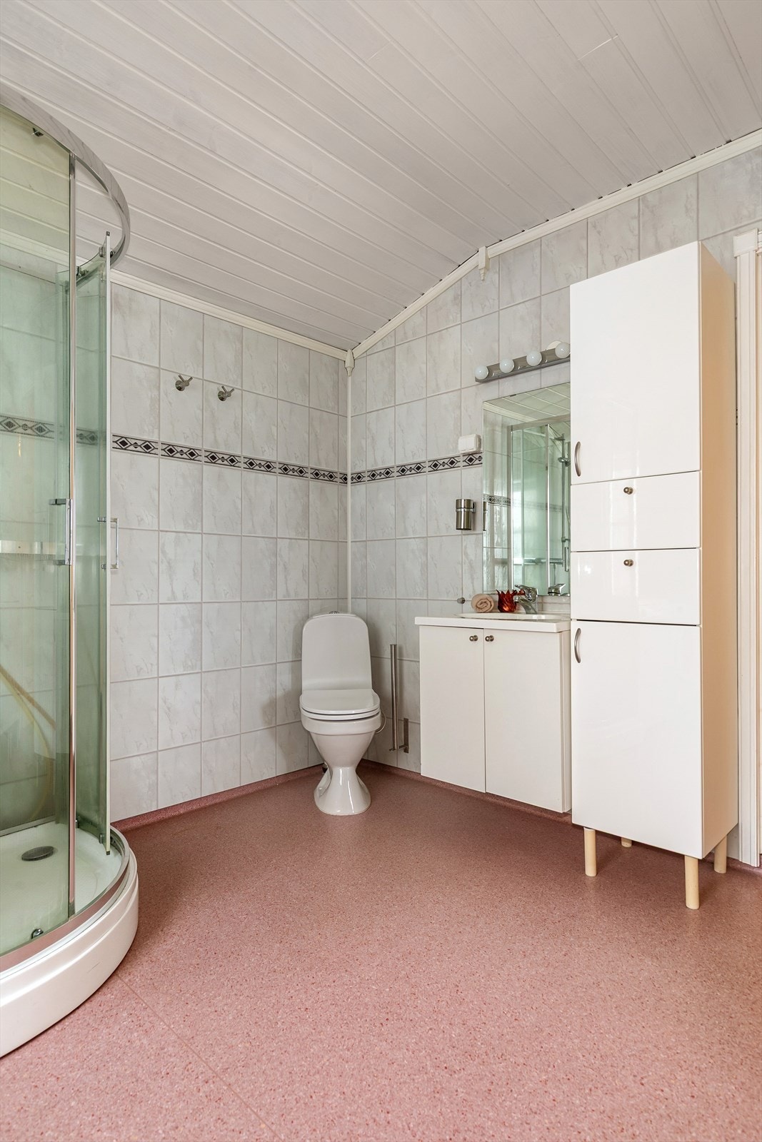 Badet er utstyrt med servant med underskap, veggskap, dusjkabinett, toalett og opplegg for vaskemaskin og tørketrommel Galleribilde