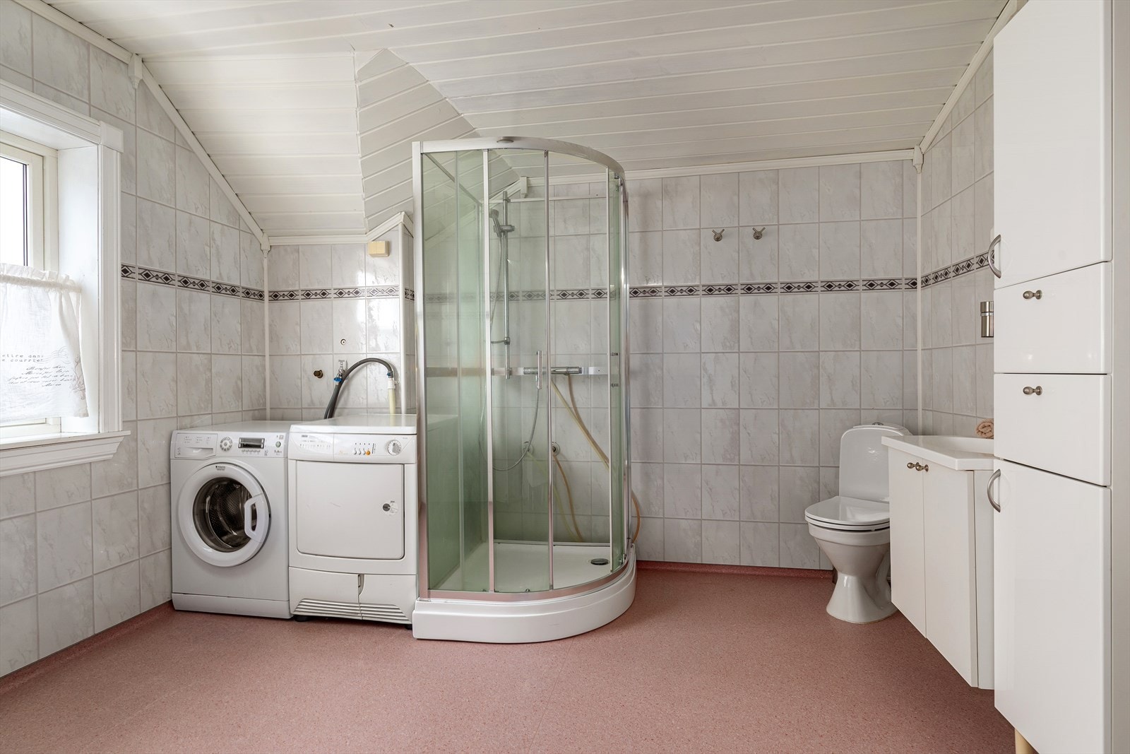 Romslig baderom med belegg på gulv og flislagte vegger Galleribilde