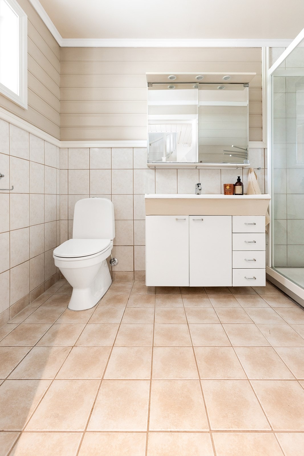 Innredningen består av servant med underskap, overskap med speildører og lys, høyskap, dusjkabinett med skyvedør og frittstående toalett. Galleribilde