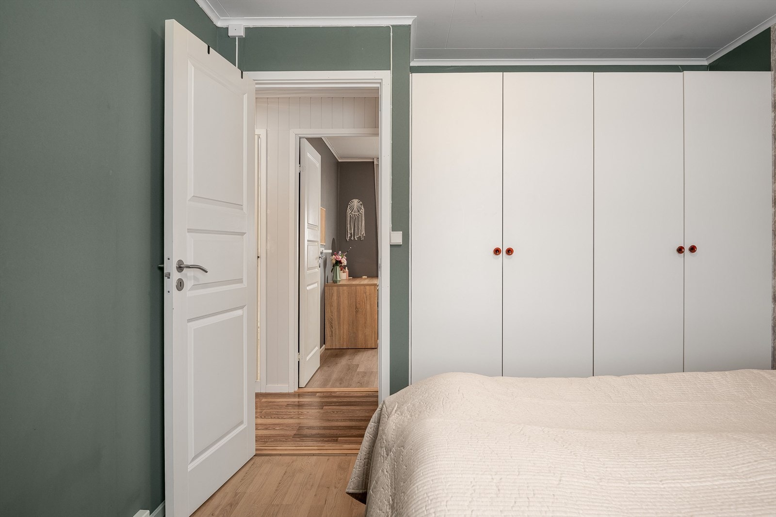 God standard med laminat på gulv og glatte overflater malt i en fin grønnfarge med en lys tapetsert kontrastvegg. Galleribilde