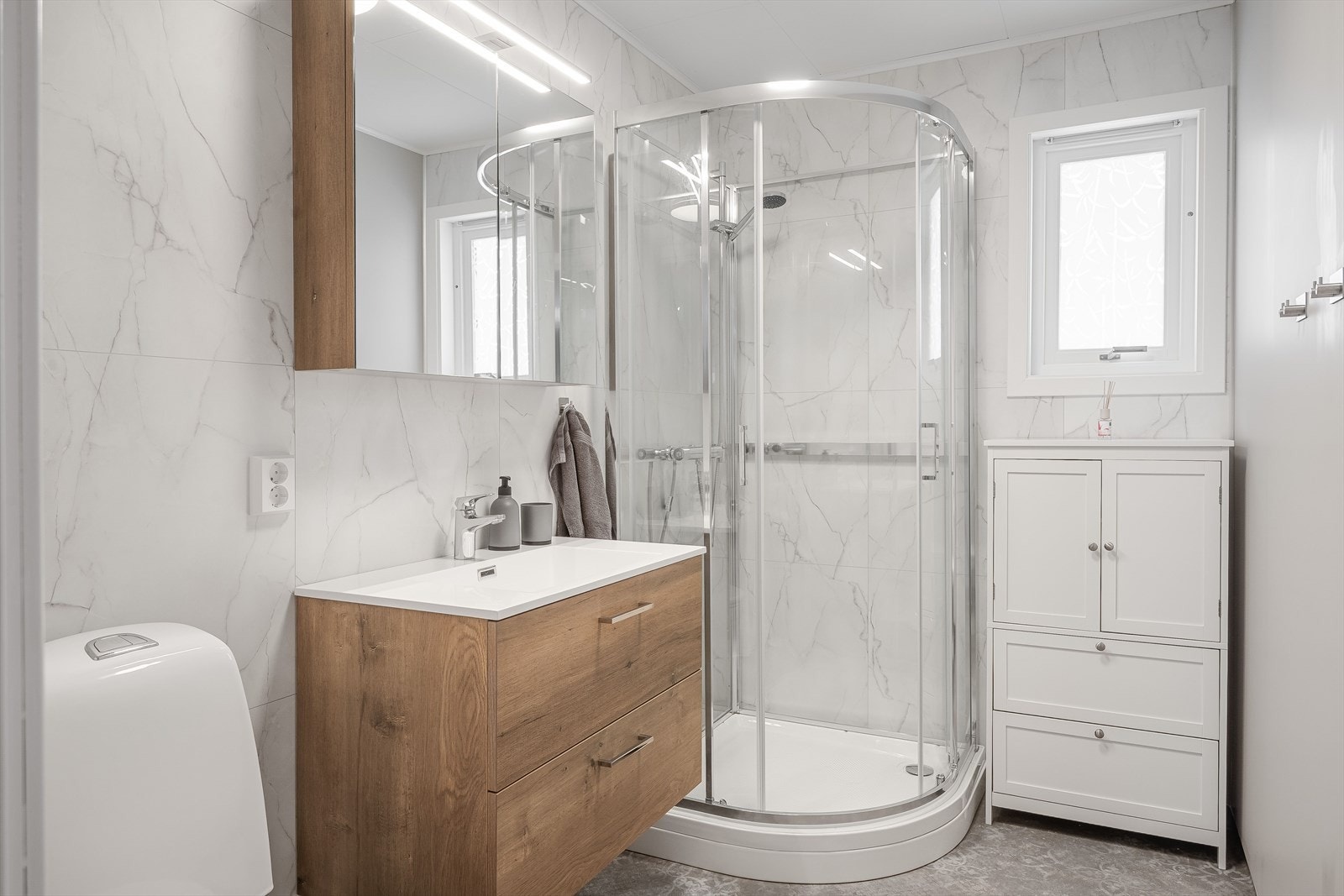 Lyst og delikat baderom som ble pusset opp i 2025. Baderommet har våtromsbelegg på gulv med gulvvarme, lyse våtromsplater på veggene og mekanisk avtrekk. Galleribilde