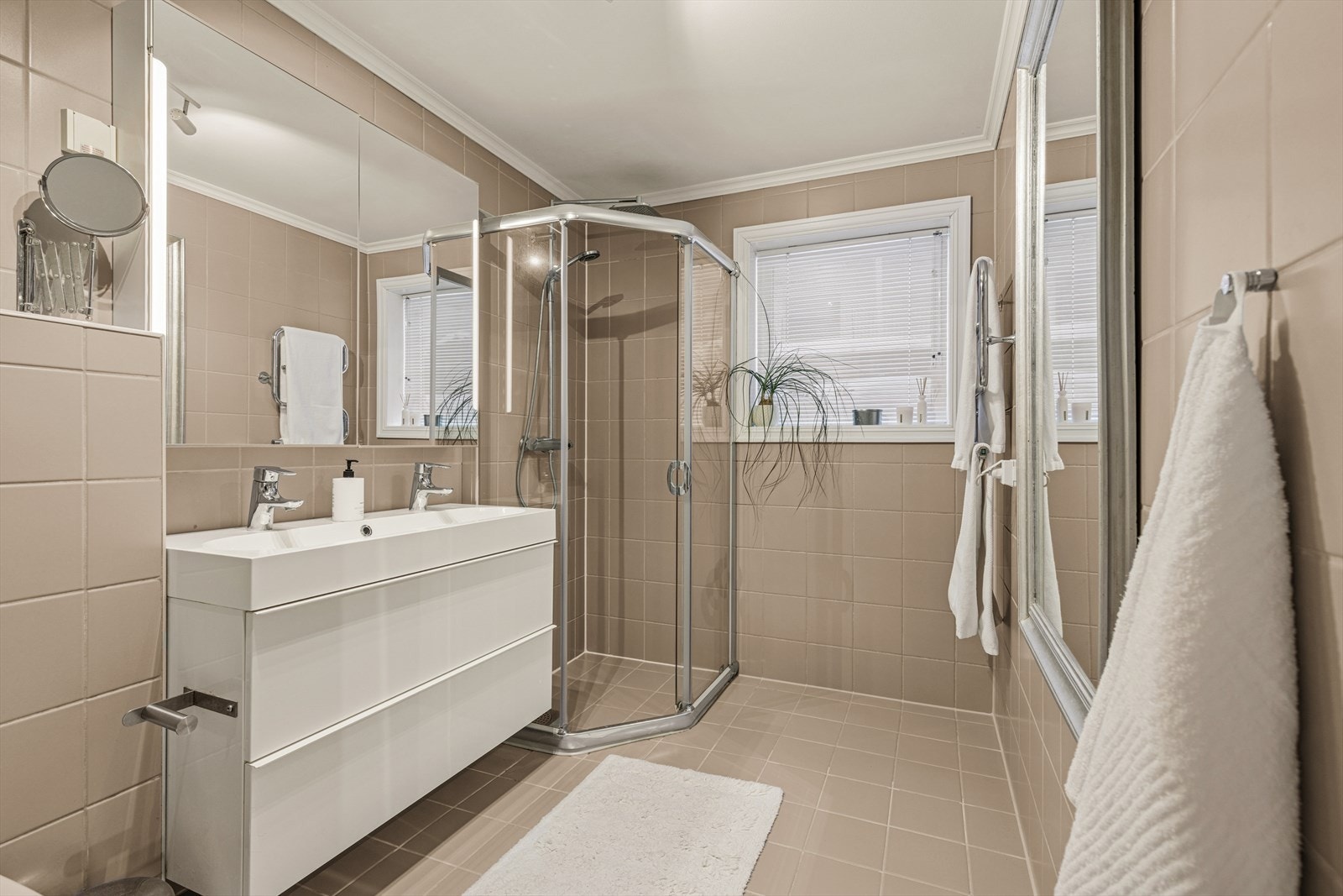 Badet består av speilskap med belysning, servant med seksjon, dusjhjørne og veggmontert toalett. Galleribilde