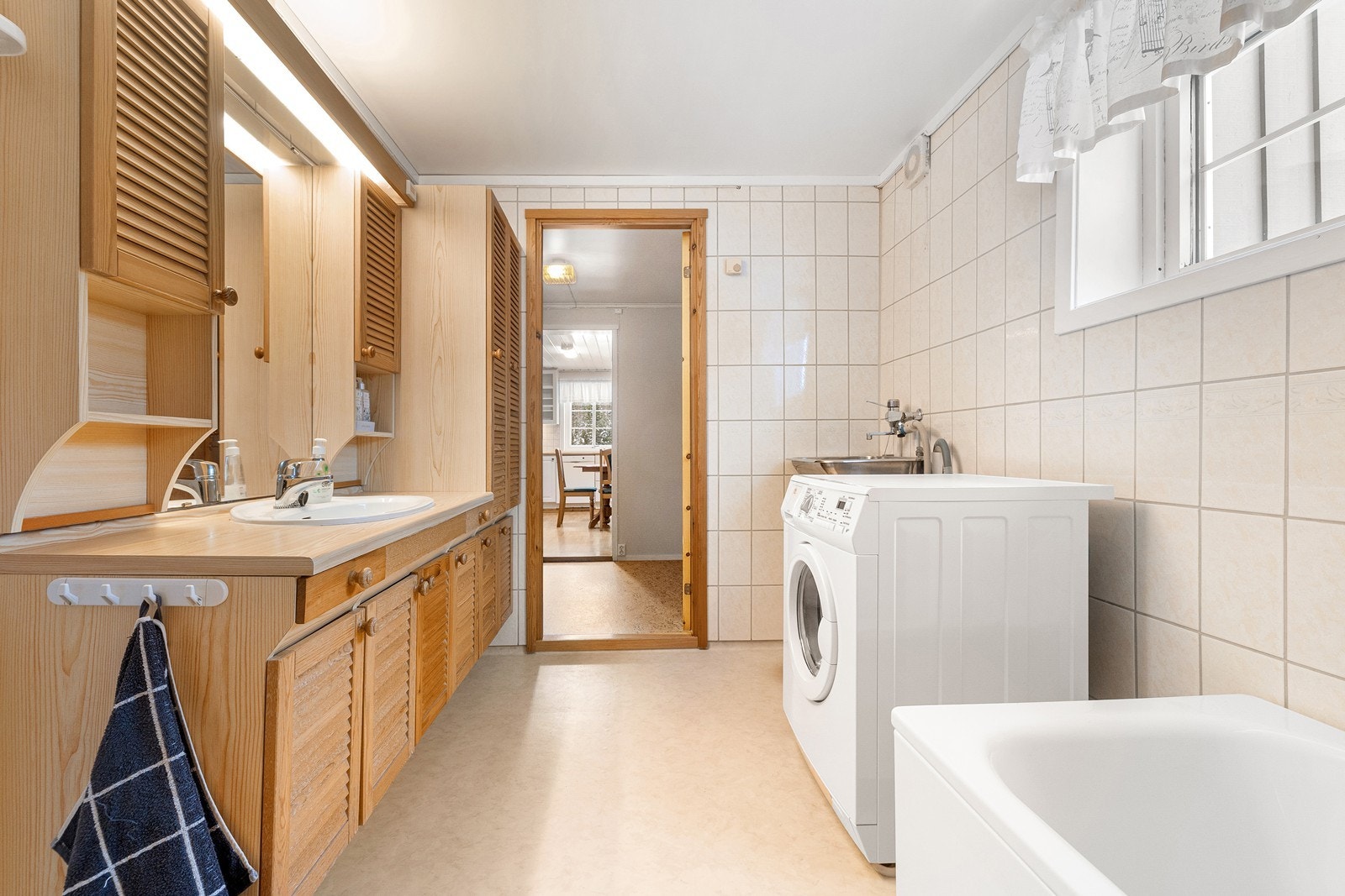 Badet er innredet med servant i baderomsinnredning med god skapplass, skyllekum, tilhørende vaskemaskin, badekar, dusjarmatur og toalett. Galleribilde