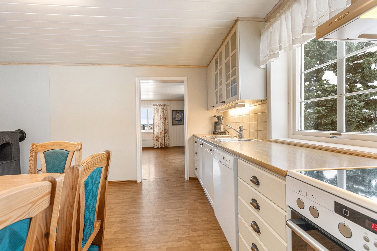 Kjøkkeninnredningen har lyse, glatte fronter, noen overskap med glassfront og laminert benkeplate. Galleribilde