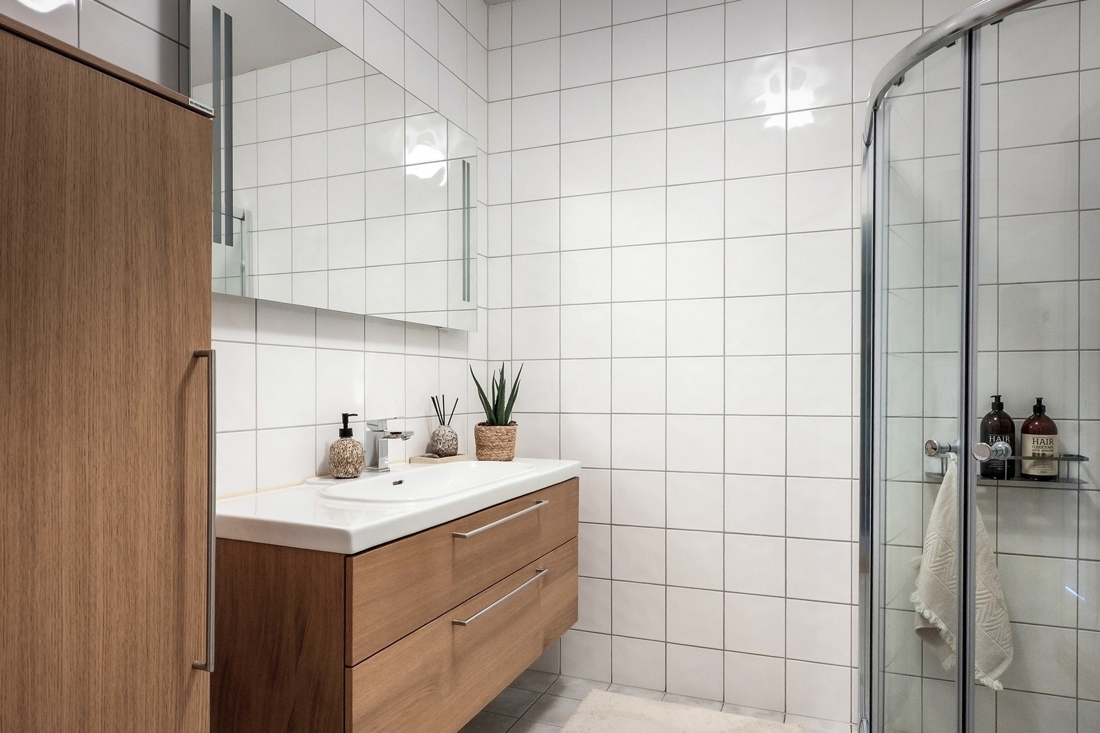 Badet i andre etasje er fra byggeår og har flislagte overflater. Rommet er utstyrt med servant med tilhørende innredning, vegghengt toalett og dusjhjørne Galleribilde