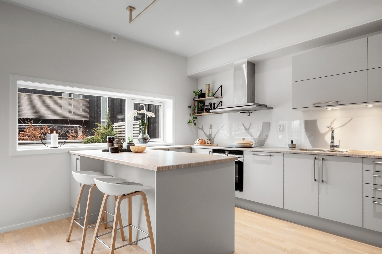 Halvøya gir ekstra arbeidsflate og skaper en naturlig overgang mot stuen, samtidig som den har plass til barstoler for uformelle måltider og hyggelige samlingspunkter Galleribilde