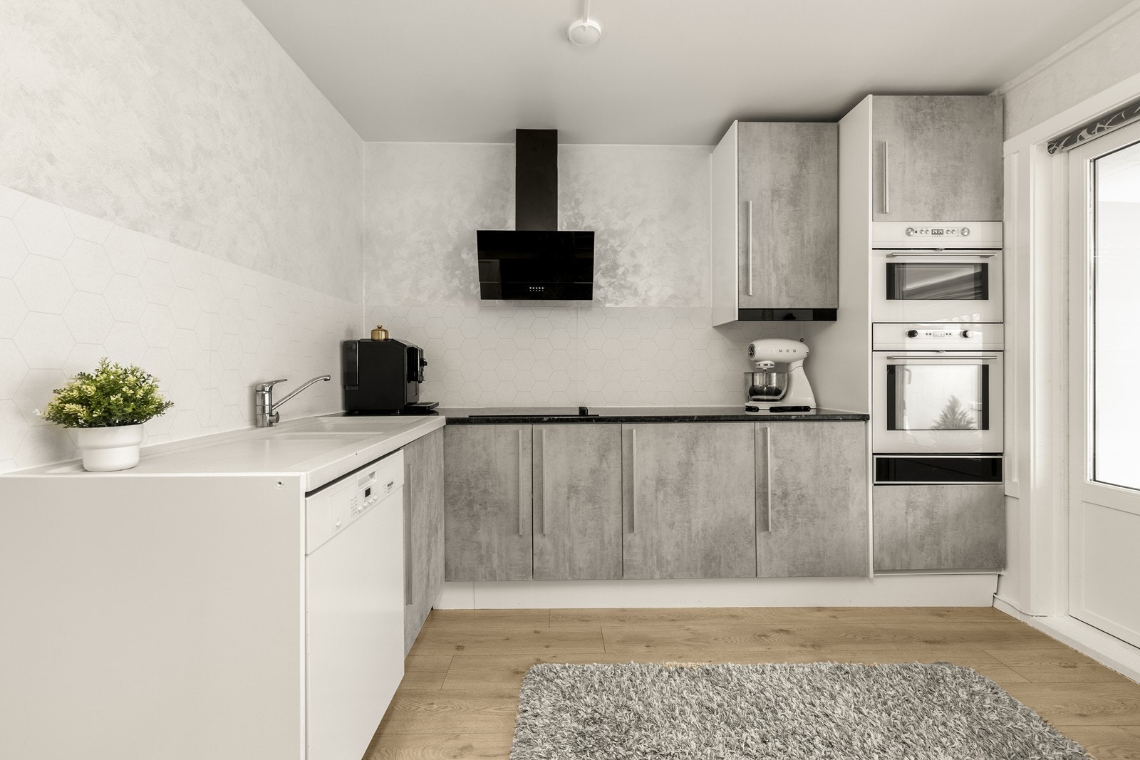 Moderne kjøkkeninnredning med glatte, folierte fronter og integrert stekeovn og mikrobølgeovn. Galleribilde