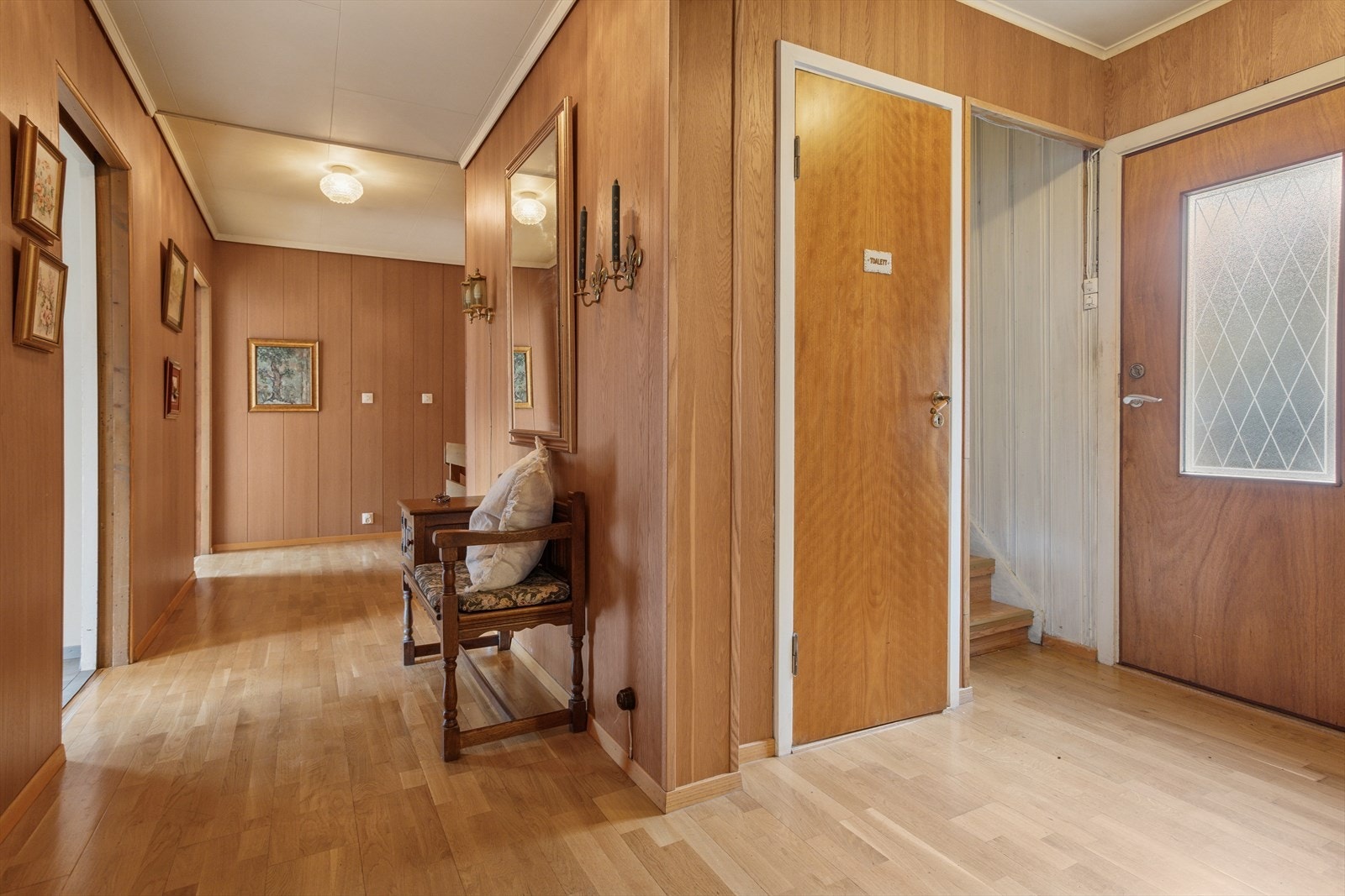 Romslig gang i boligens hovedplan med klassiske detaljer og god plass til oppbevaring. Her er det også WC-rom, samt trapp opp til boligens øverste plan. Galleribilde