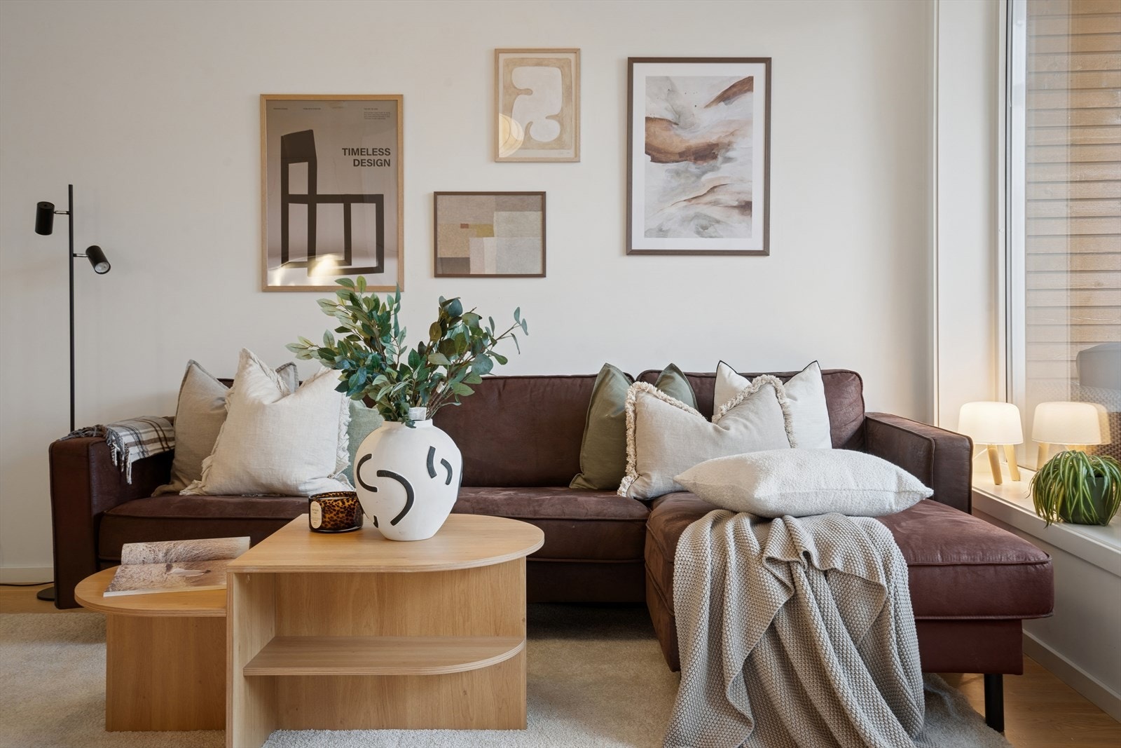 Stuen bader i naturlig lys gjennom de brede vindusflatene, noe som løfter romfølelsen og gir interiøret et elegant, levende spill gjennom dagen. Galleribilde