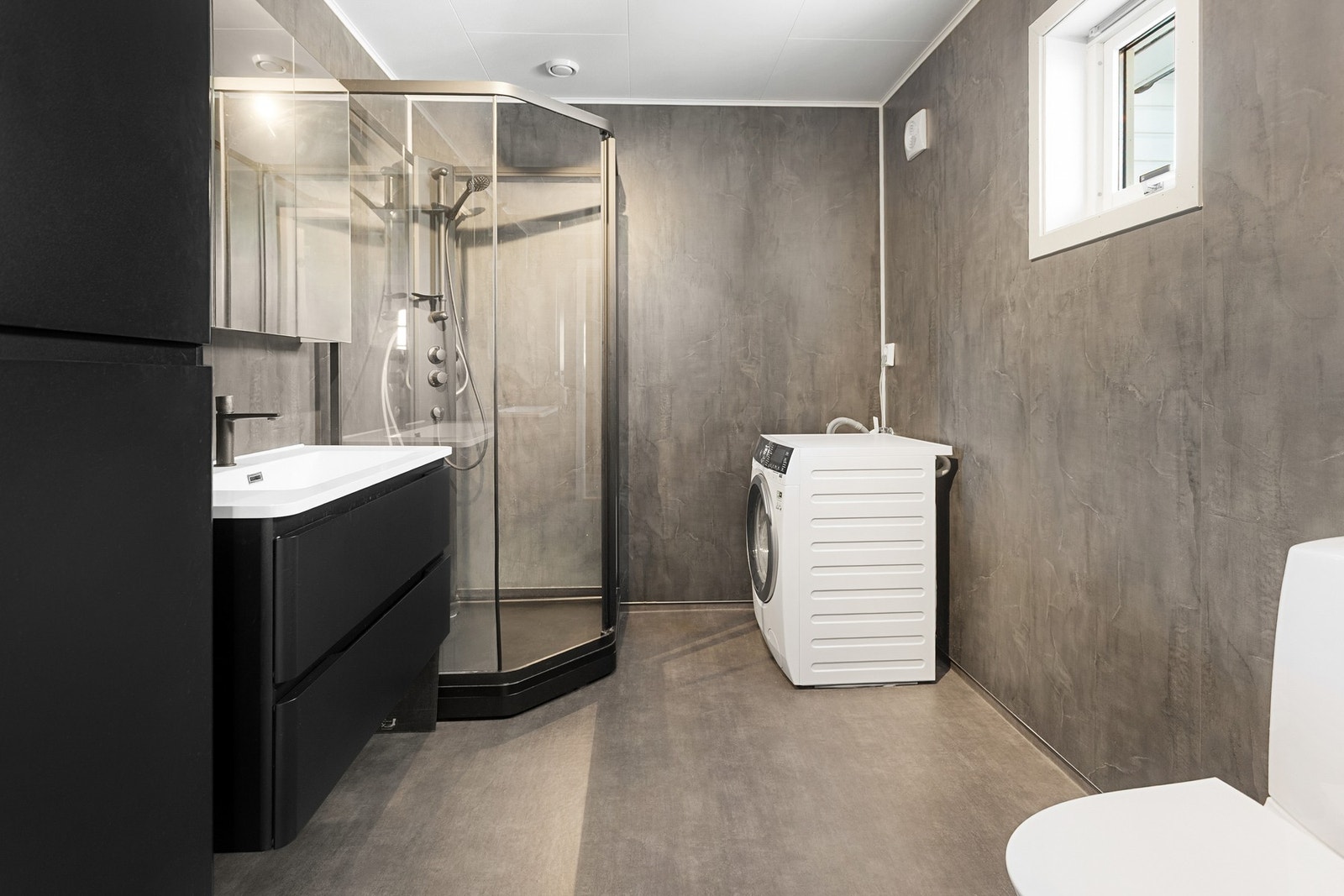 Bad/vaskerom - 6,5 kvm. Oppusset i 2023! Utstyrt med servantskap, høgskap, dusjkabinett, toalett og opplegg for vaskemaskin Galleribilde