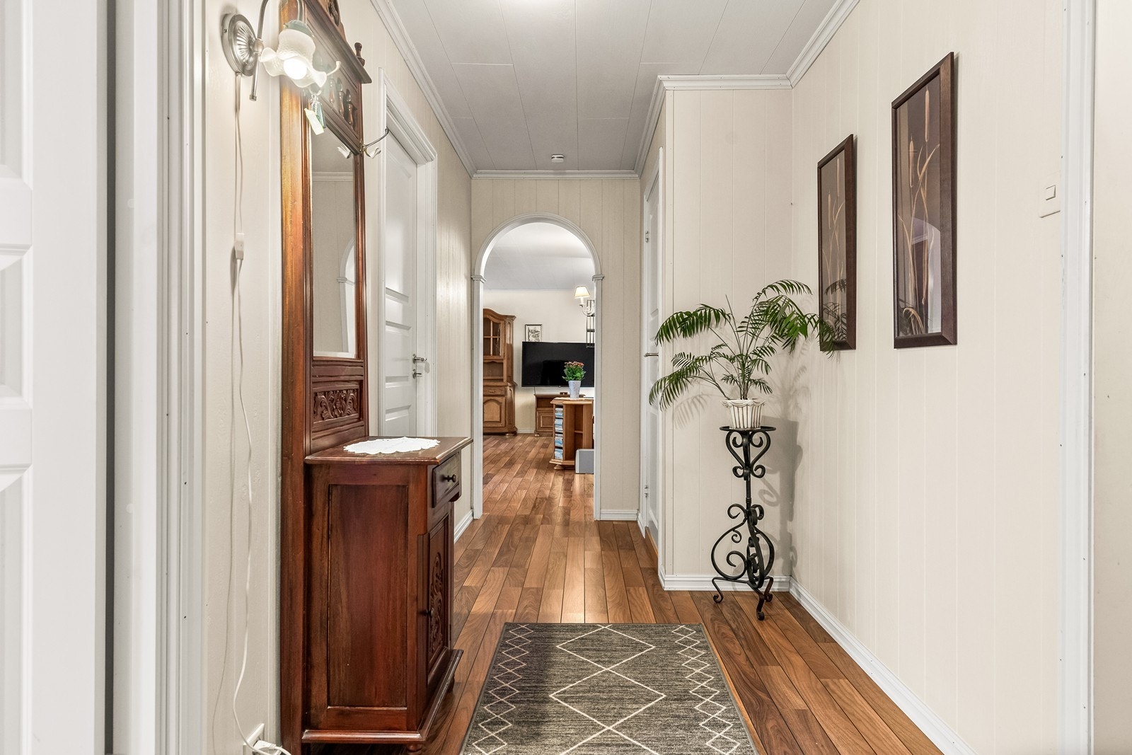 Gangen har slettmalte vegger og en bue som leder inn til stuen. Galleribilde