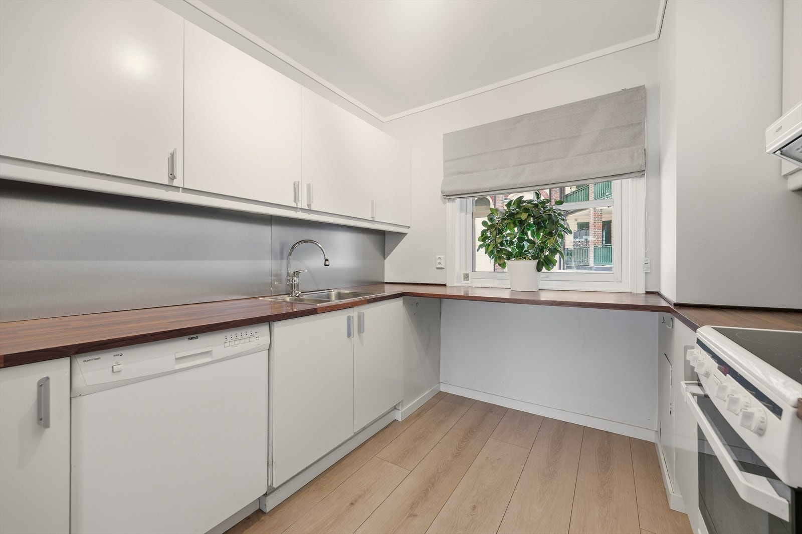 Kjøkken med glatte fronter, stålplate over kjøkkenbenk og benkeplate i laminat Galleribilde