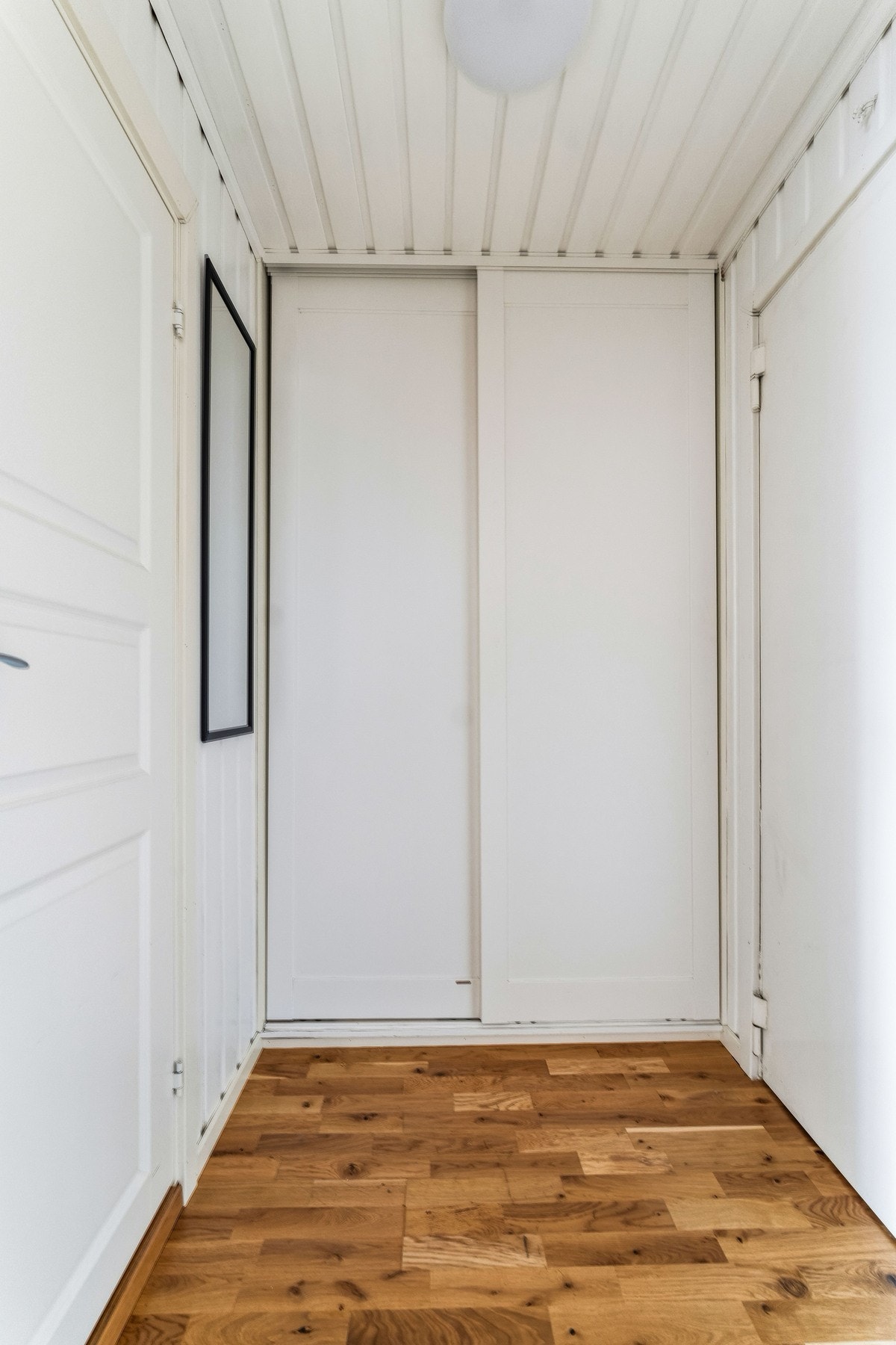 Lys og tiltalende entre med parkett på gulv og lysmalte veggflater. Praktisk skyvedørsgarderobe er bygget inn i veggen m/opplegg for vaskemaskin. Galleribilde