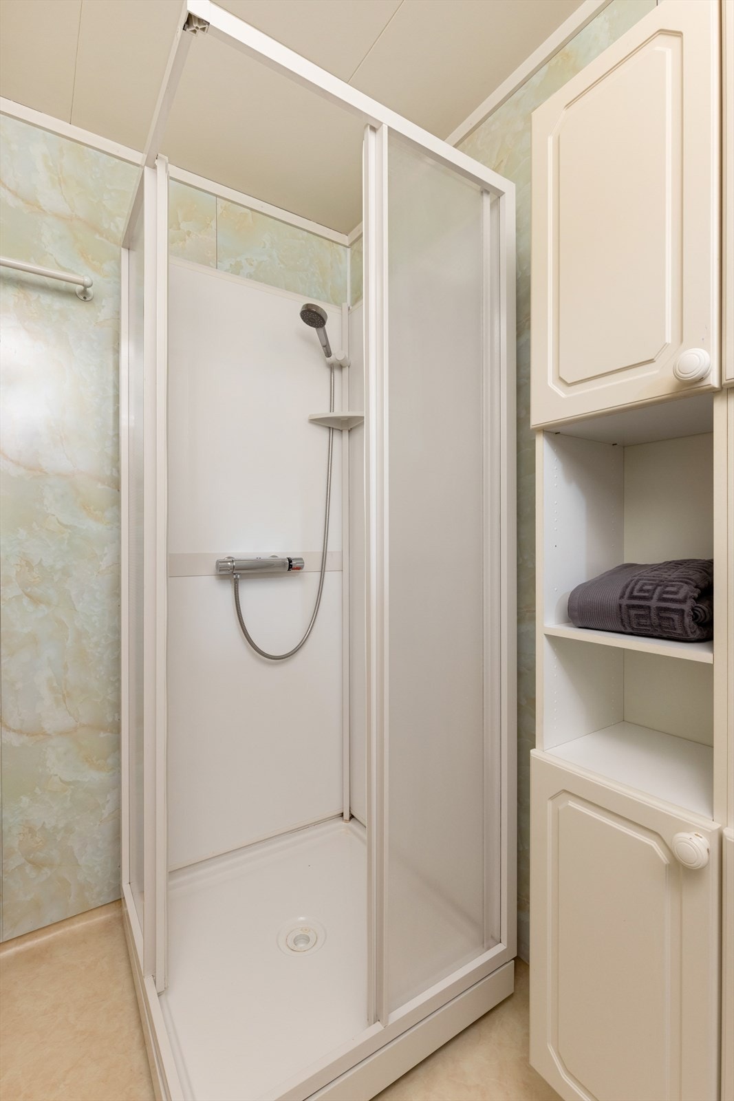 Baderommet er innredet med servant på innredning, dusjkabinett og speil. Galleribilde