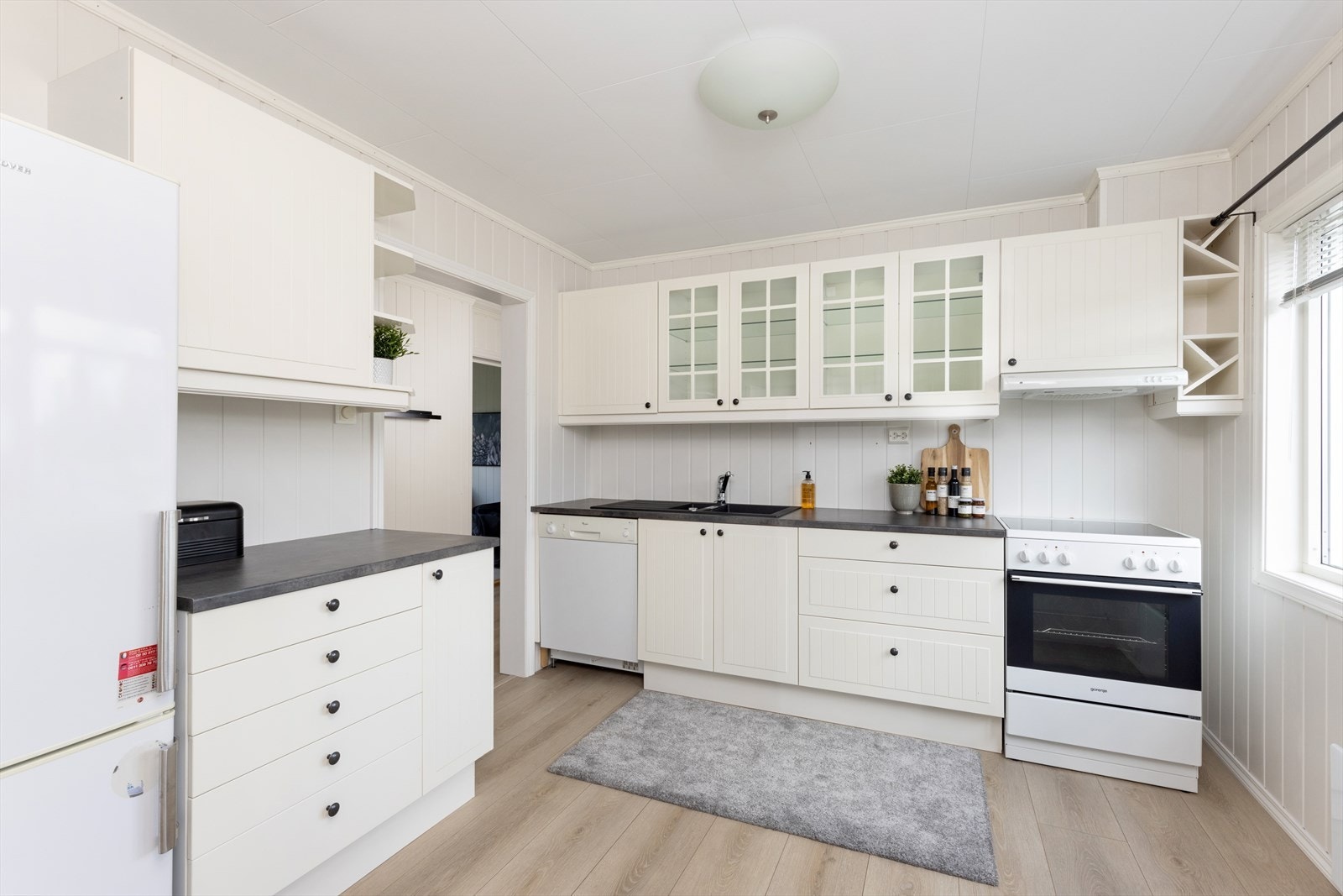 Kjøkkeninnredning med laminert benkeplate, over- og underskap, opplegg for oppvaskmaskin og kjøkkenventilator. Galleribilde